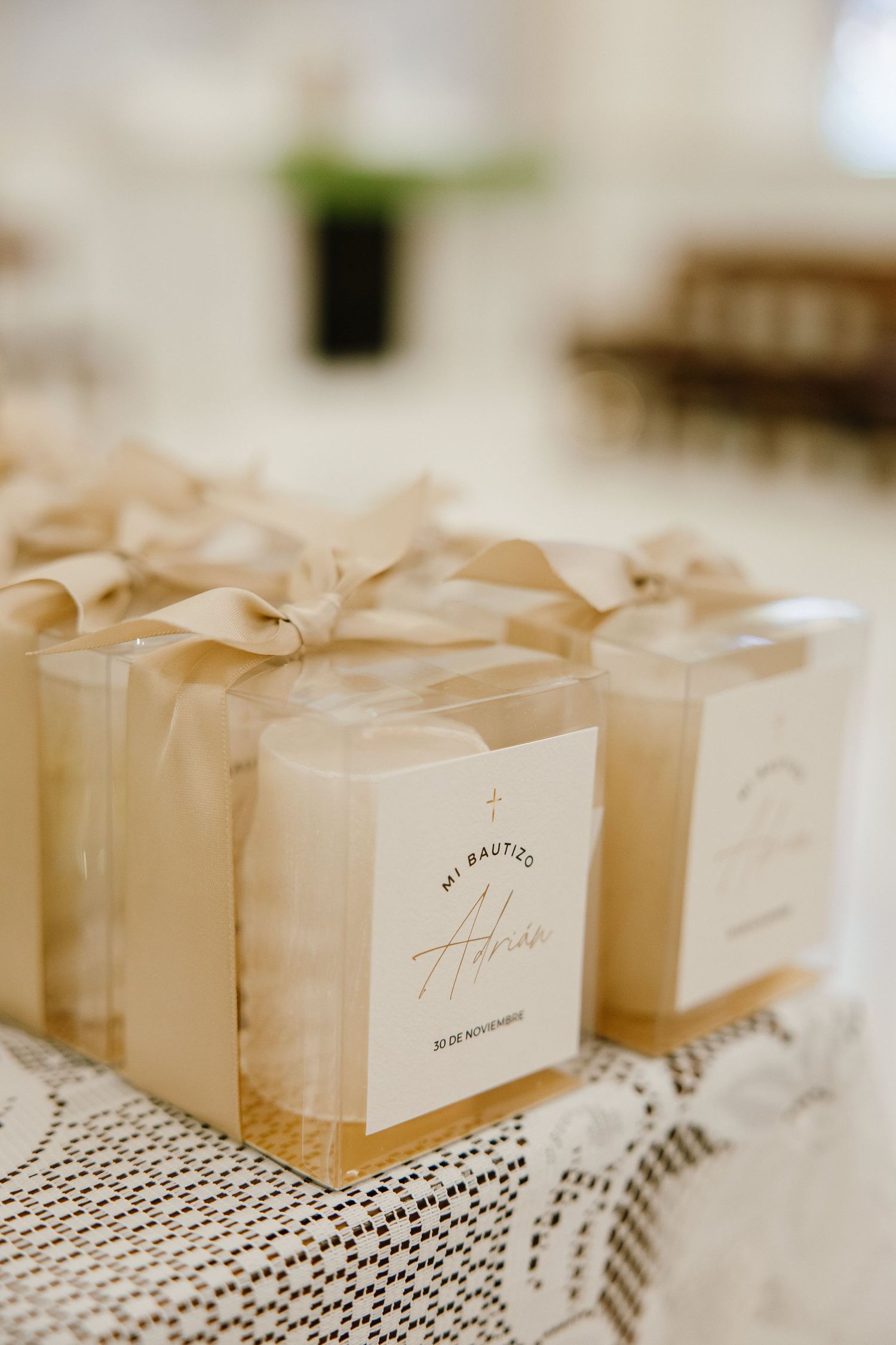 Cream-colored gift boxes with elegant bows arranged on lace tablecloth.