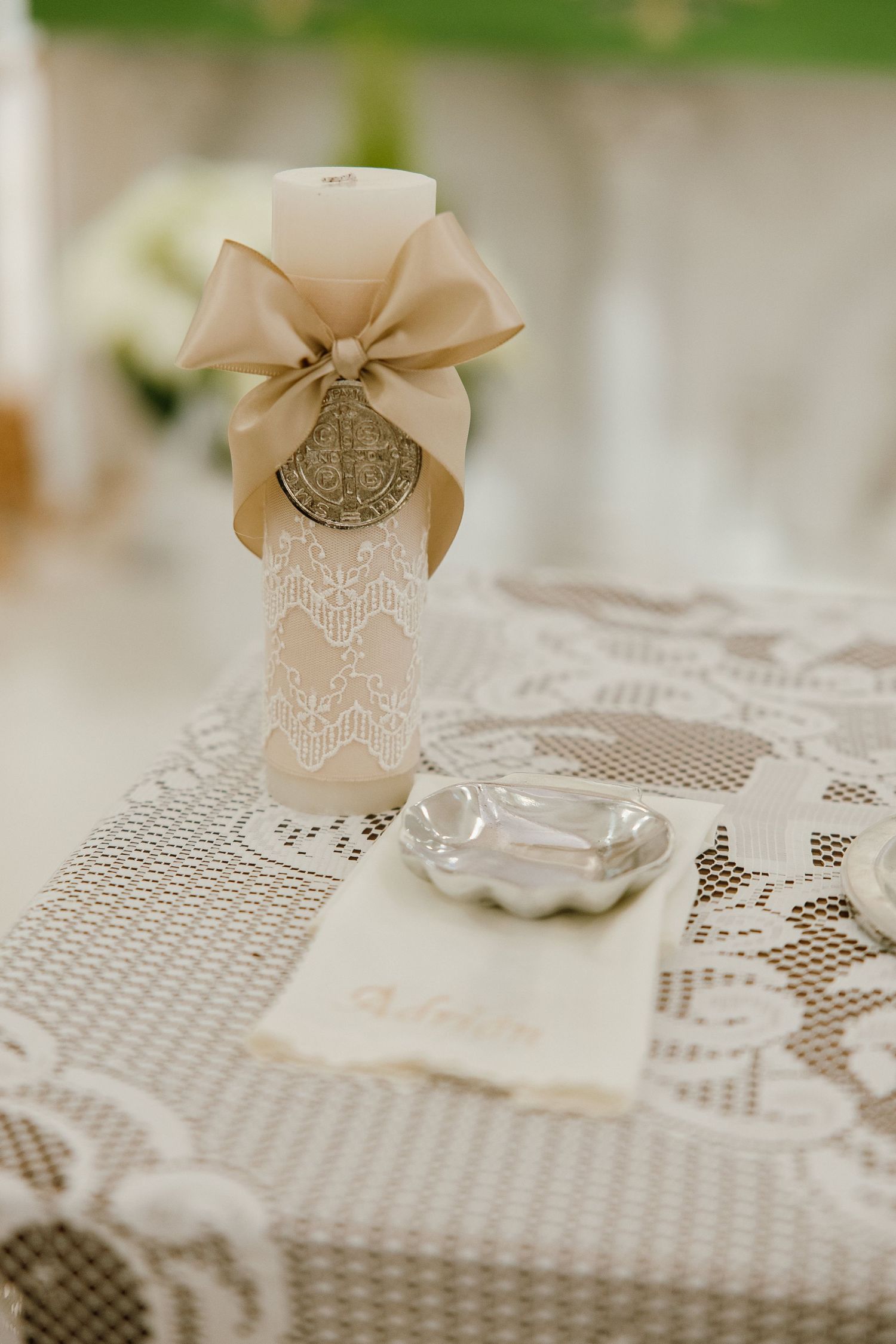 Decorative cream-colored bows and ornate details on lace wedding table setting.