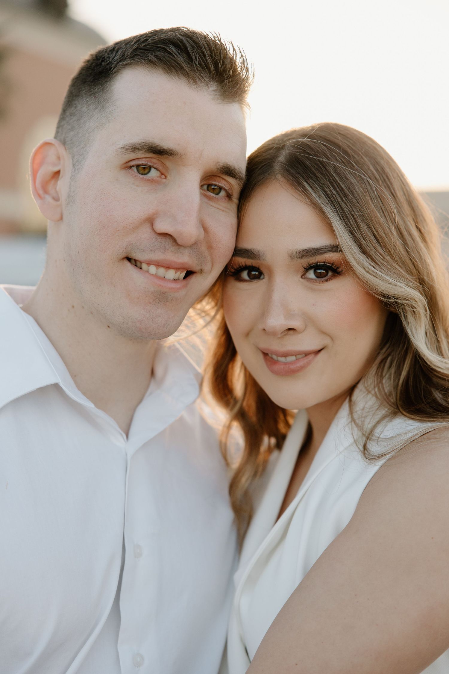 Close-up portrait of a couple in white clothing smiling at the camera.