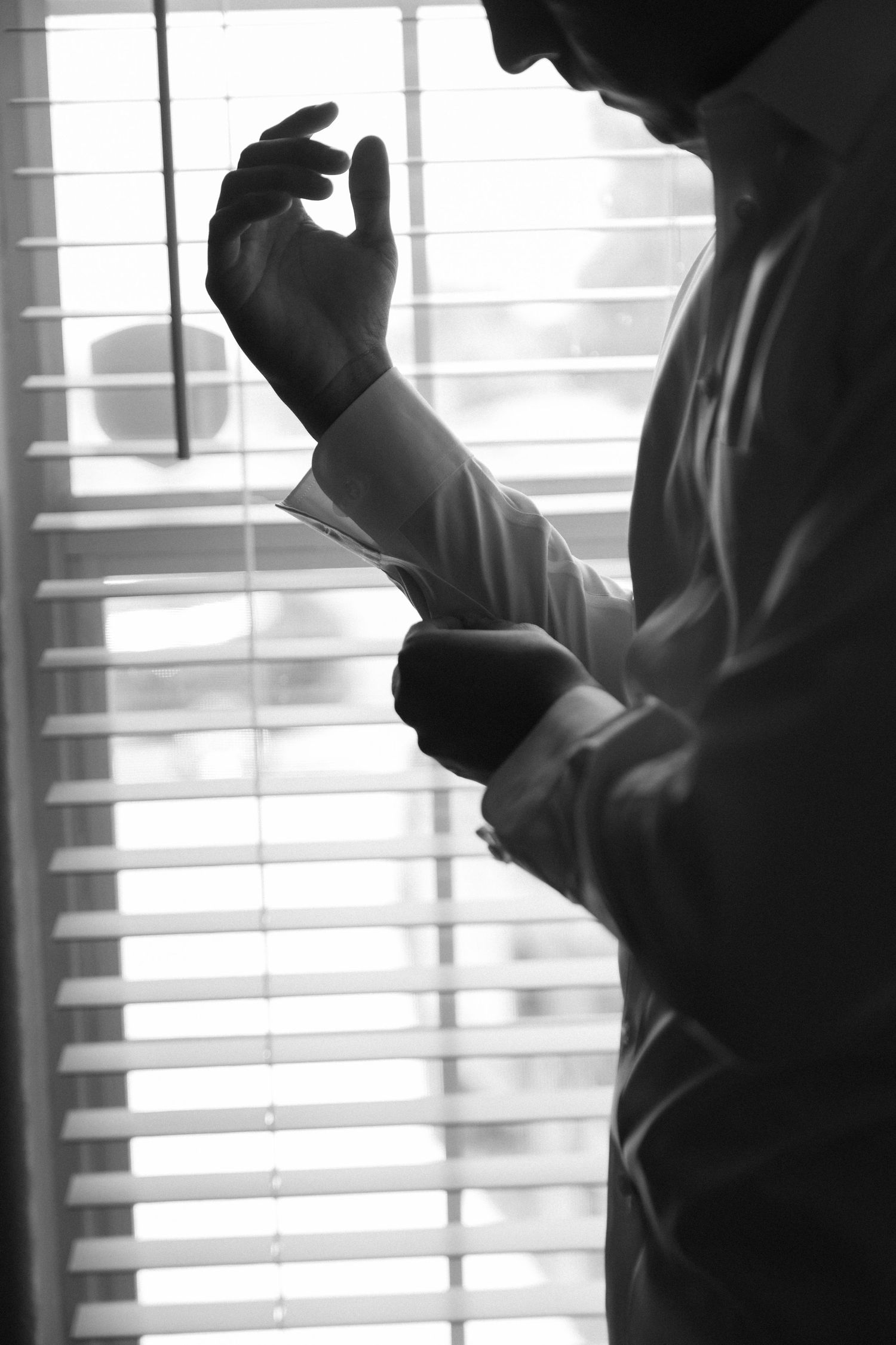 Silhouetted figures standing near windows with venetian blinds creating dramatic lighting.