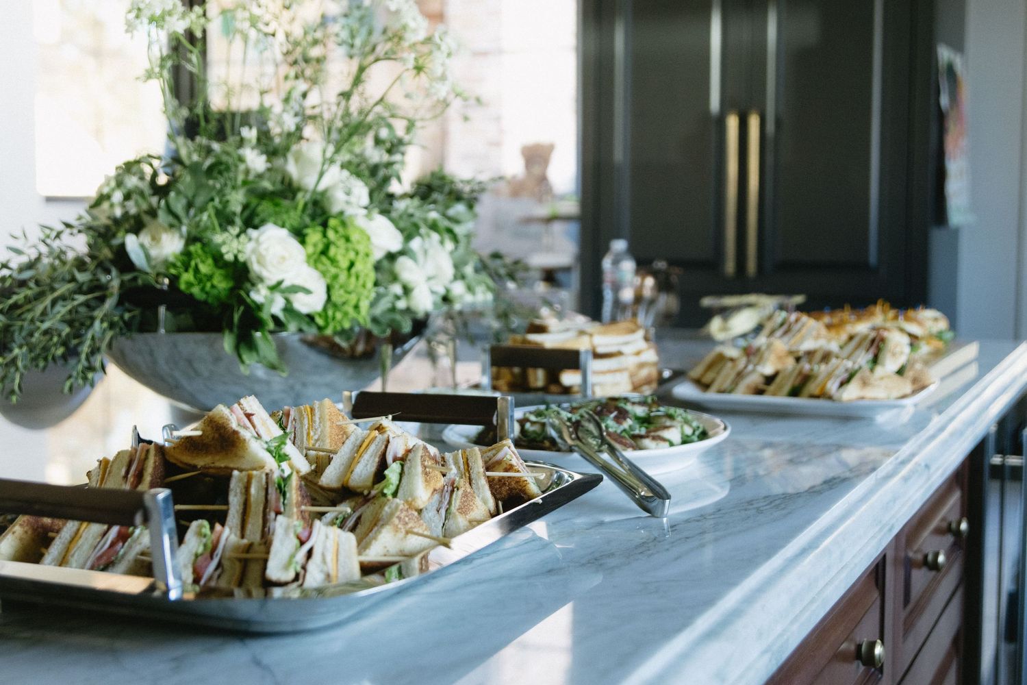 Elegant party setup with white floral arrangements and decorative elements on a dark surface.