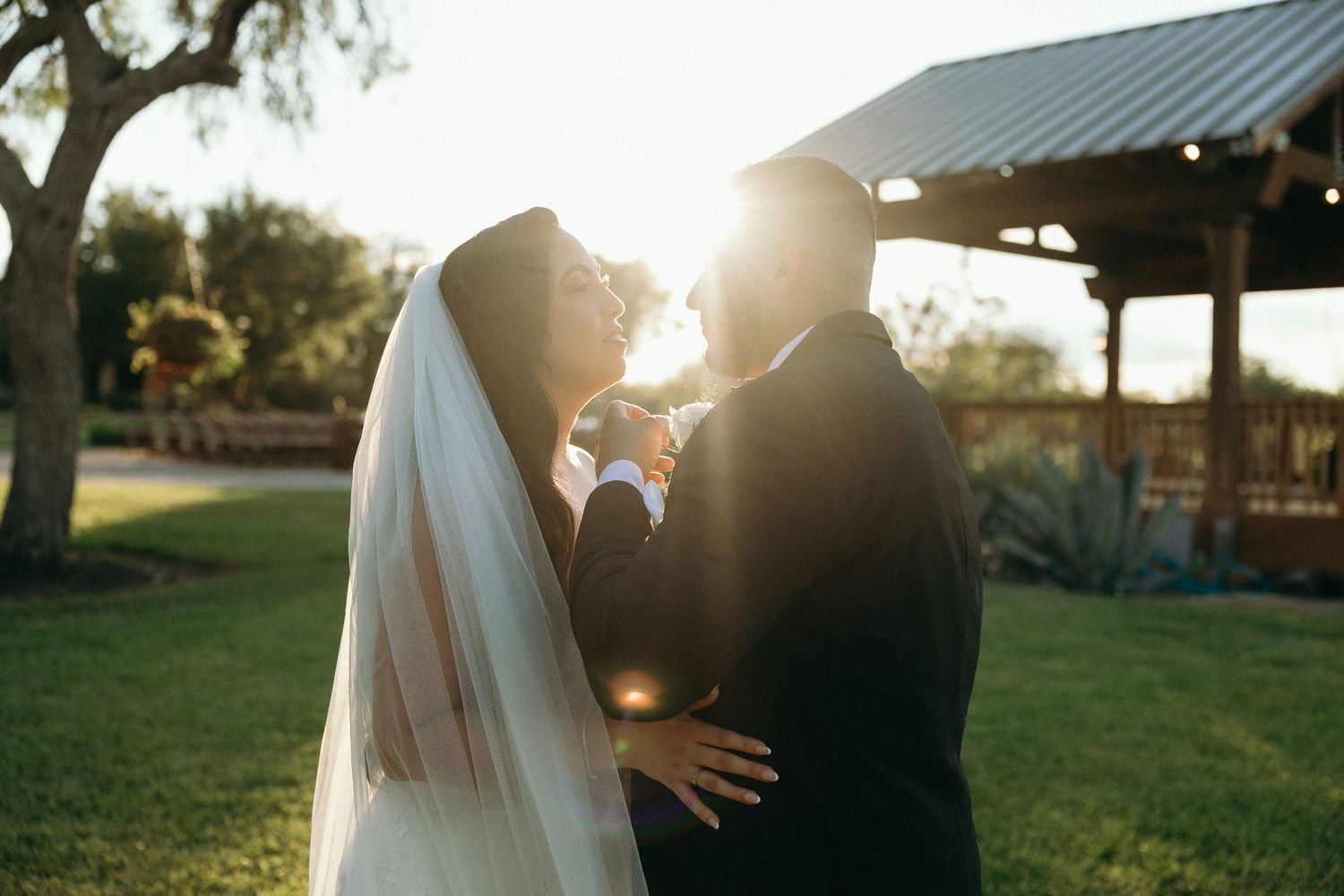 Silhouetted couple embracing during golden hour at outdoor wedding venue.
