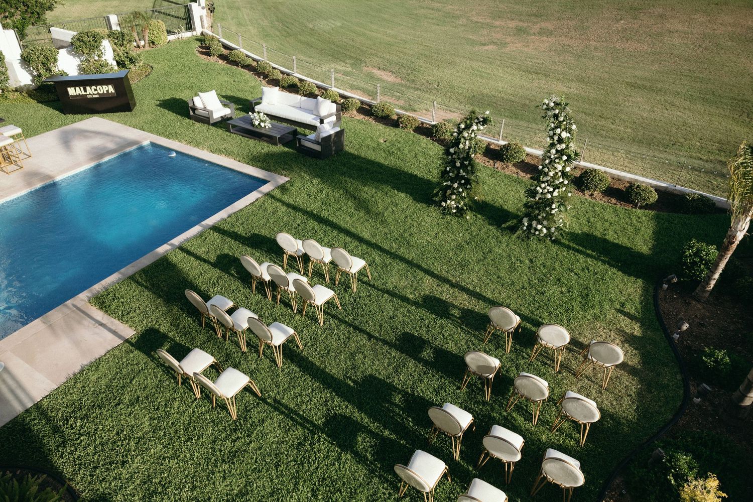 Aerial view of an outdoor event space with chairs and a swimming pool.