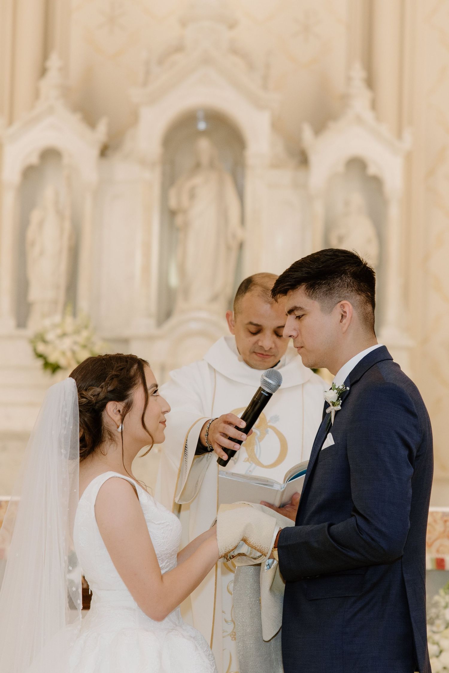 Wedding ceremony taking place in an ornate white church interior.