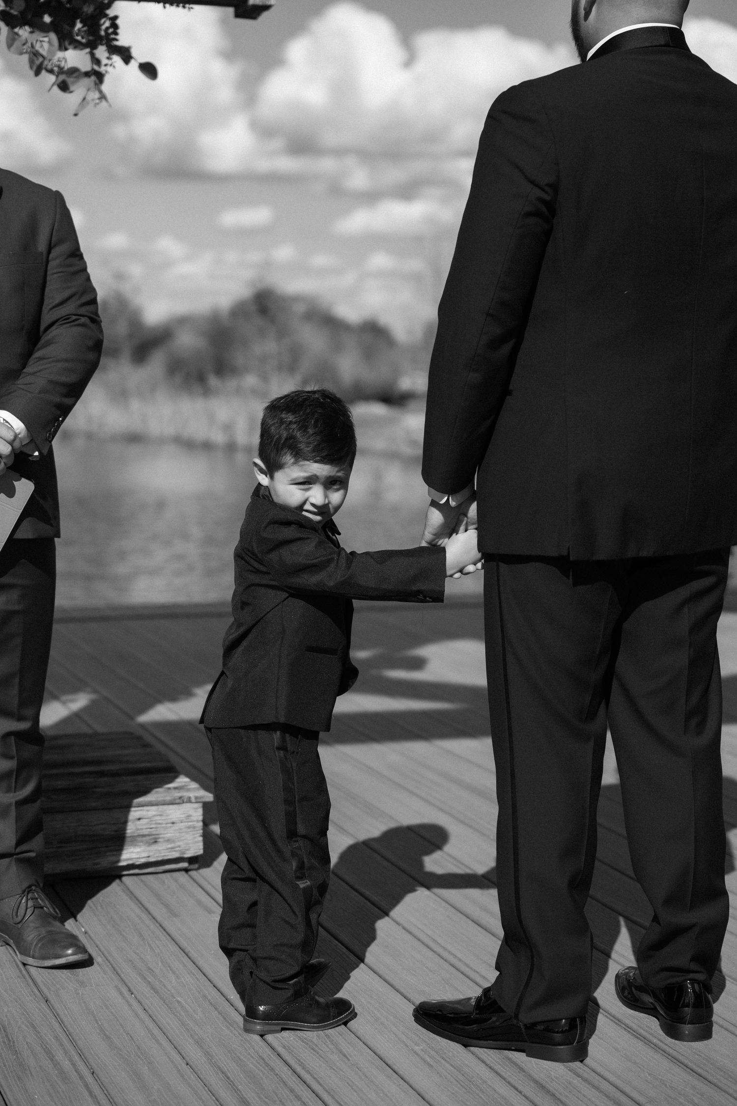 Black and white photo of formal suits and dress shoes on a wooden deck.