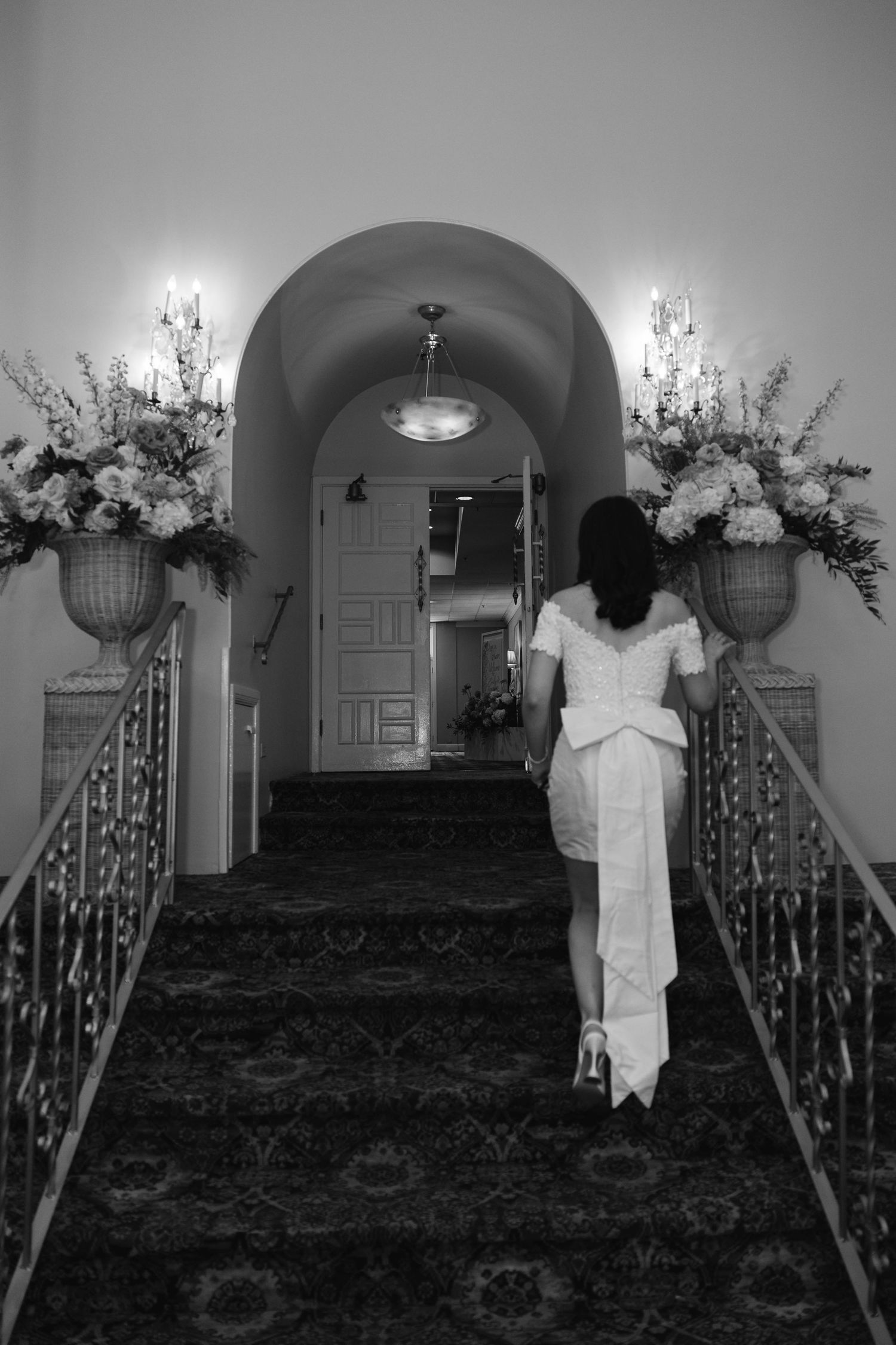 Artistic black and white sequence showing figure in white dress on grand staircase.