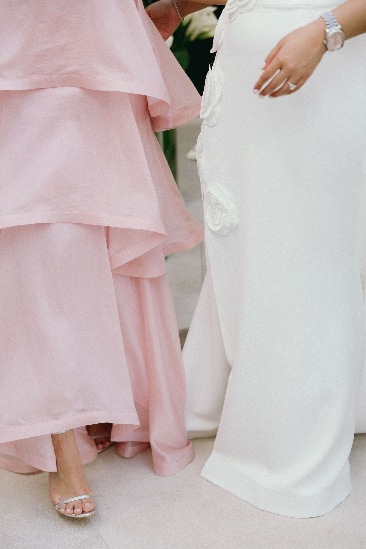 Close-up details of pink bridesmaid dresses and white wedding gown hemlines.