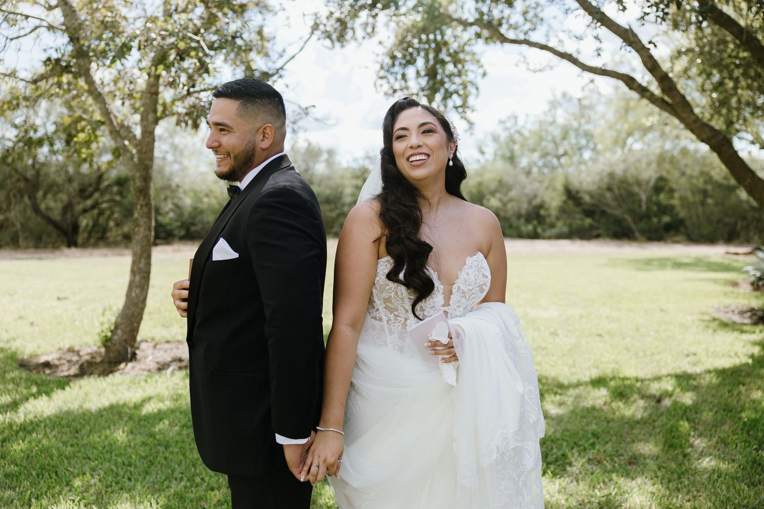 Couple poses for romantic outdoor wedding photos in a natural setting with trees.