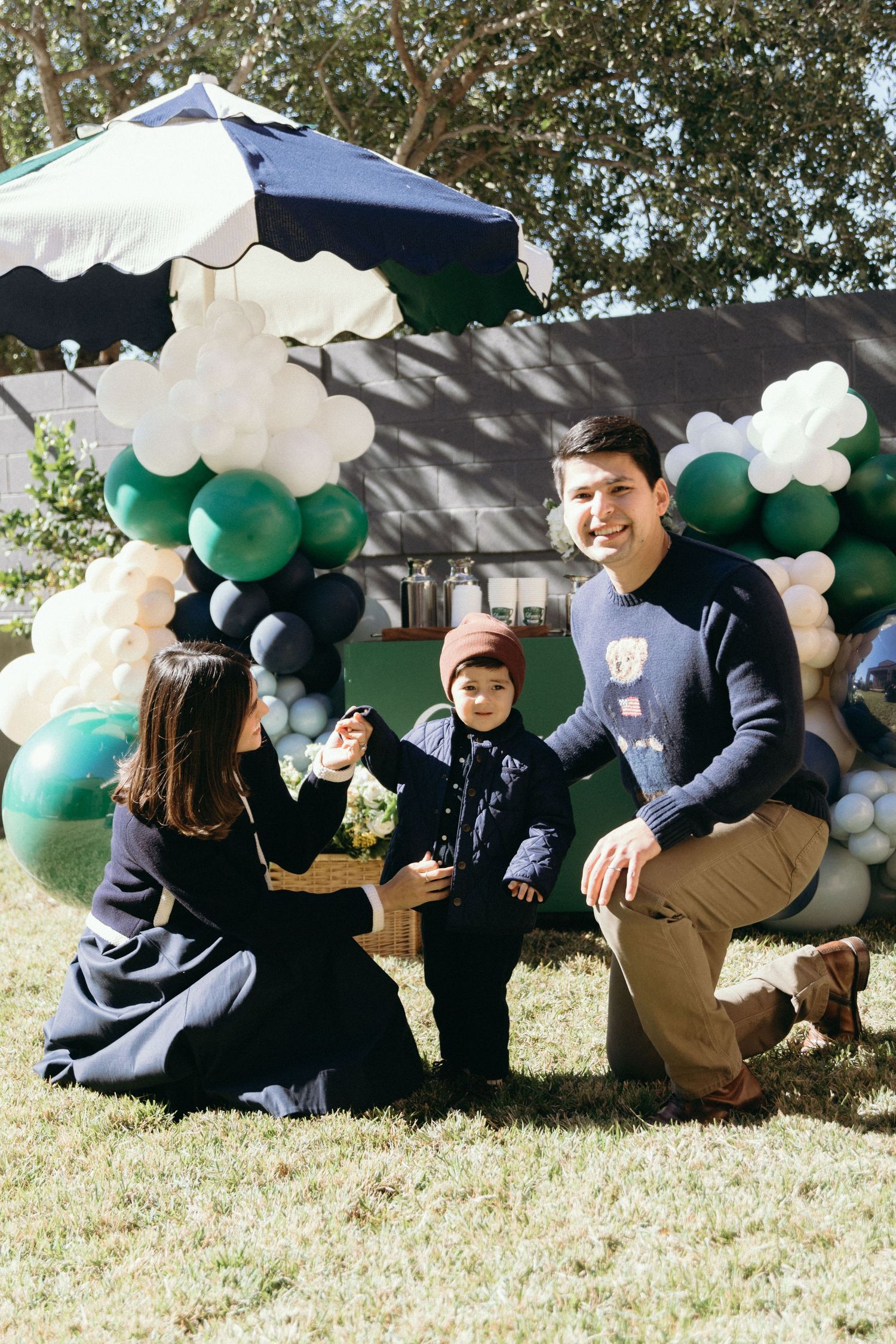 Family gathering outdoors with festive balloon decorations in green and navy colors.
