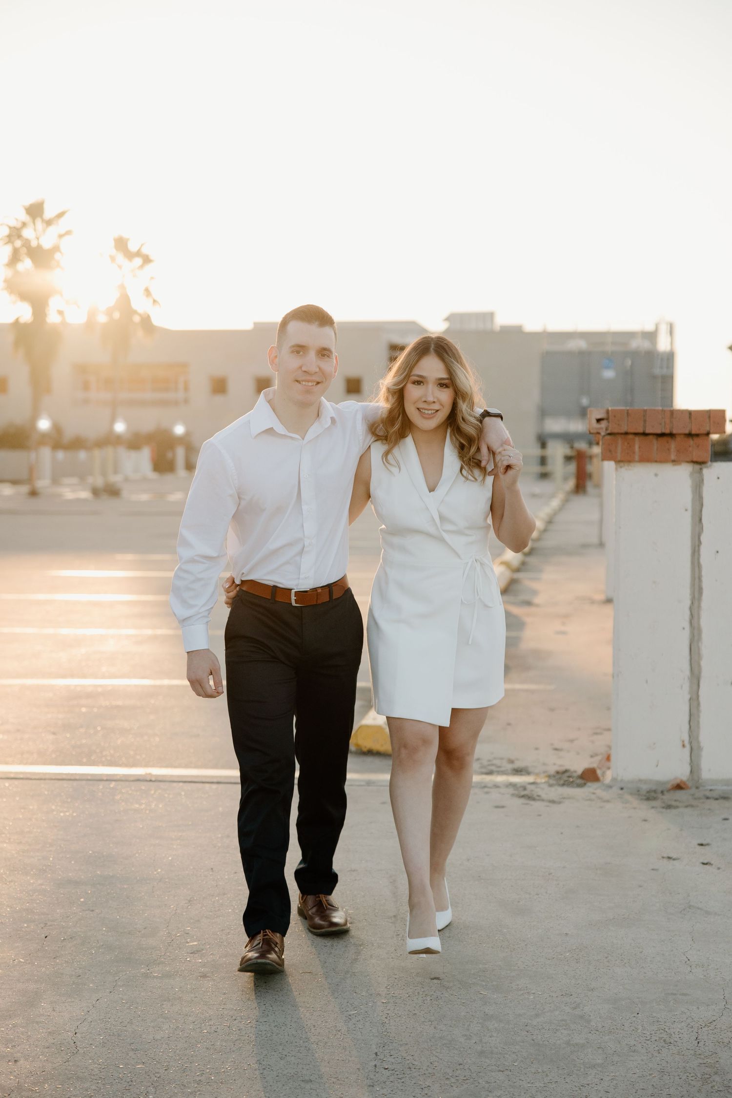 Couple in white and black outfits walking together during golden hour sunset.