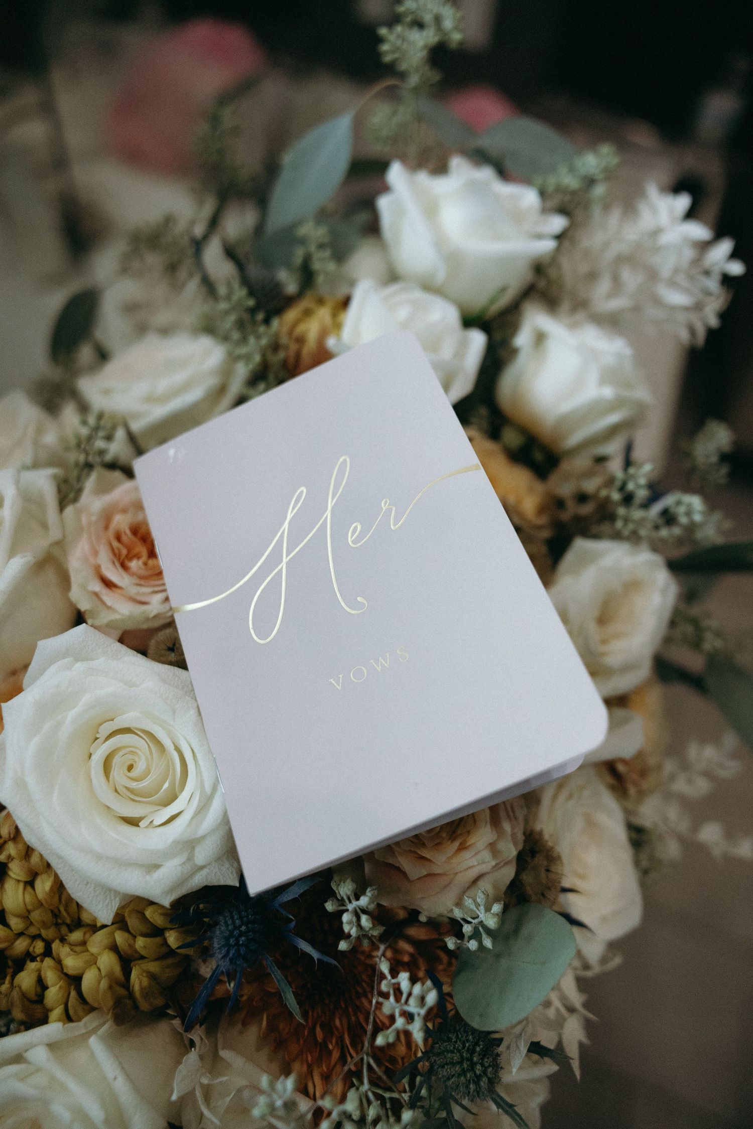 Elegant wedding stationery with calligraphy displayed among white roses and greenery.