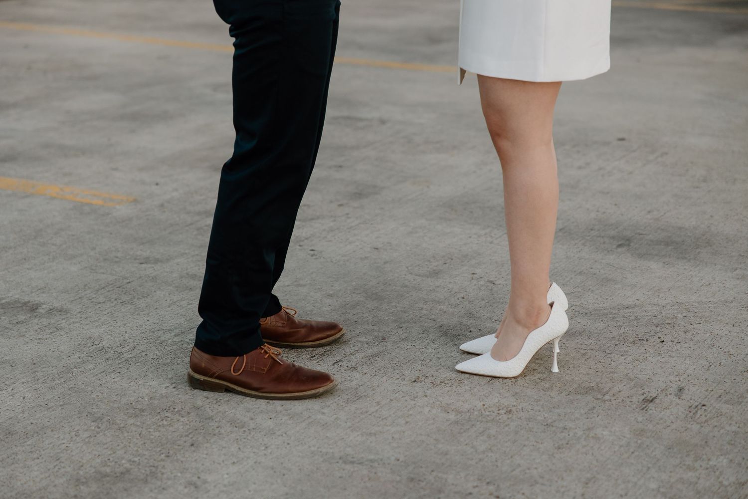 Close-up of dancing feet showing white heels and brown dress shoes.