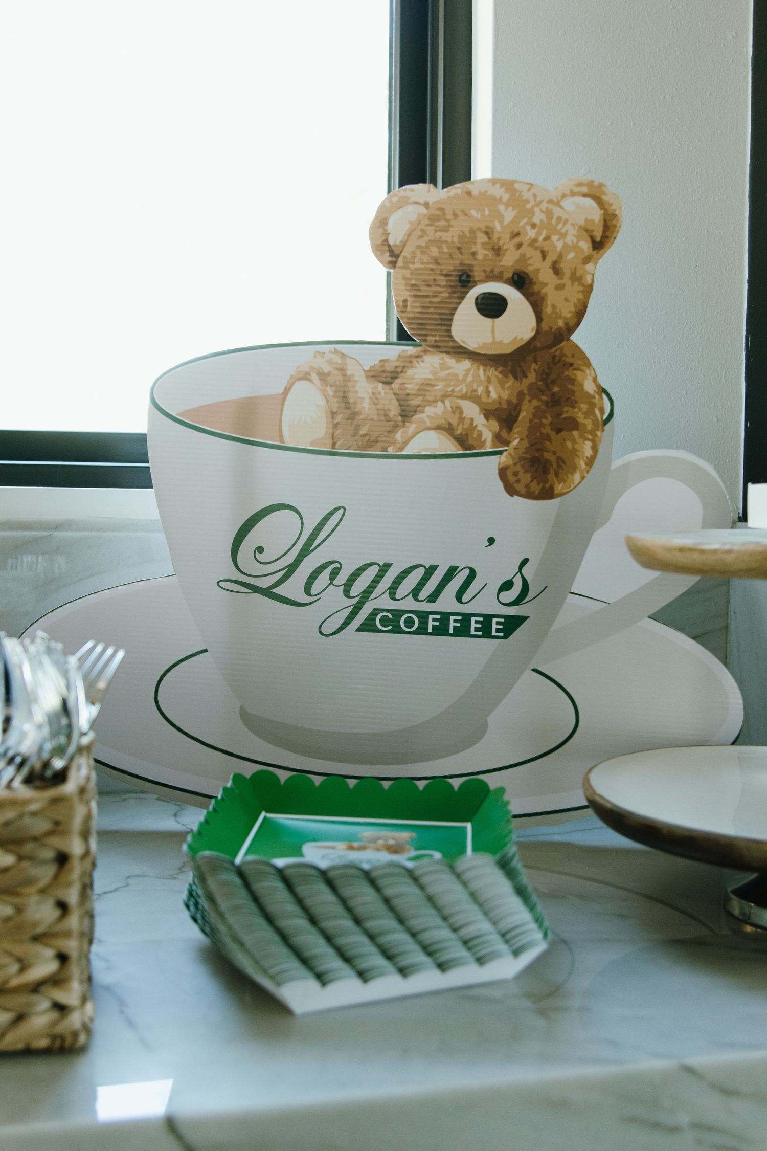 Logan's Coffee branded cups and a teddy bear displayed on mint green placemats.