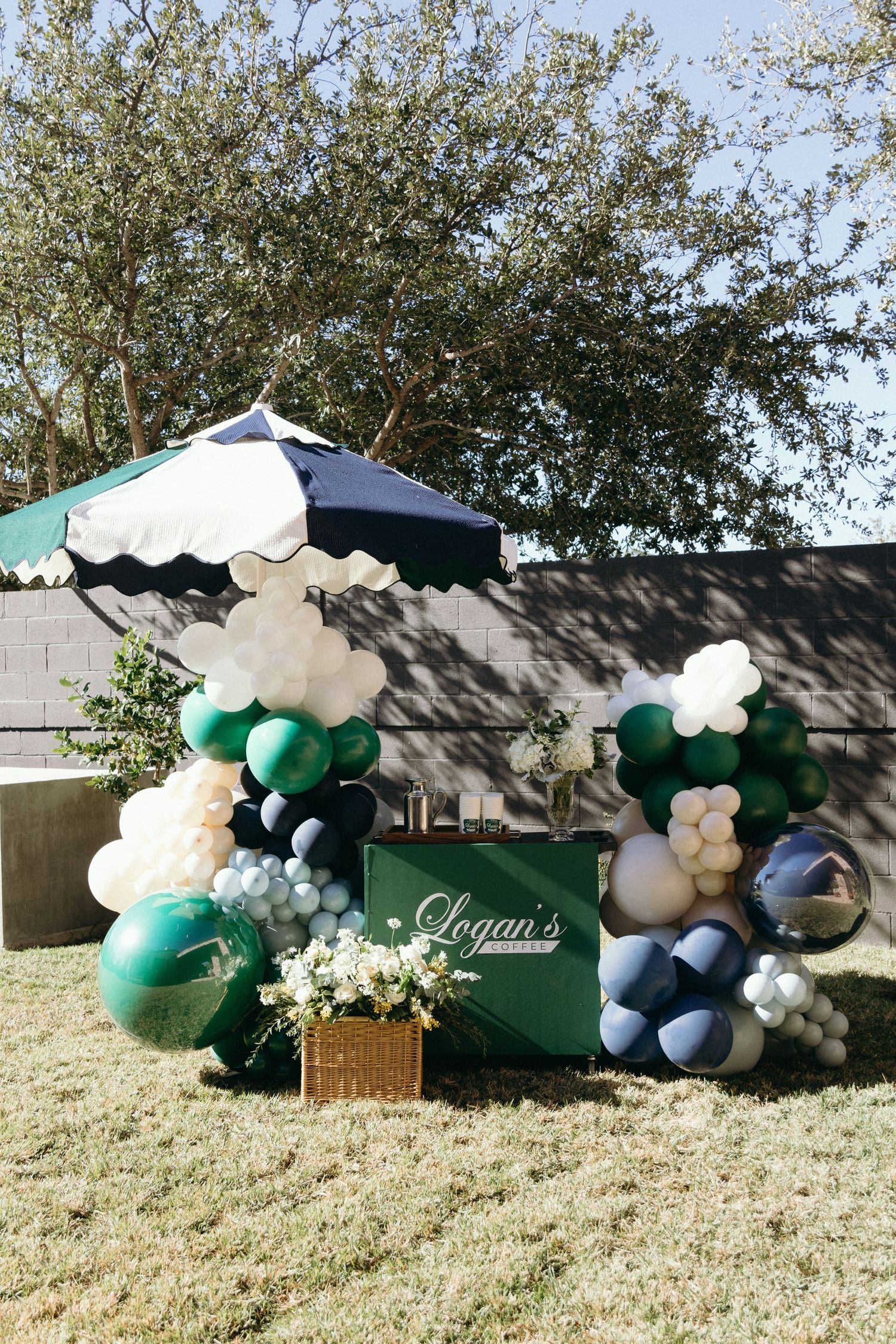 Outdoor party display with green and white balloon arrangements and decorative boxes.