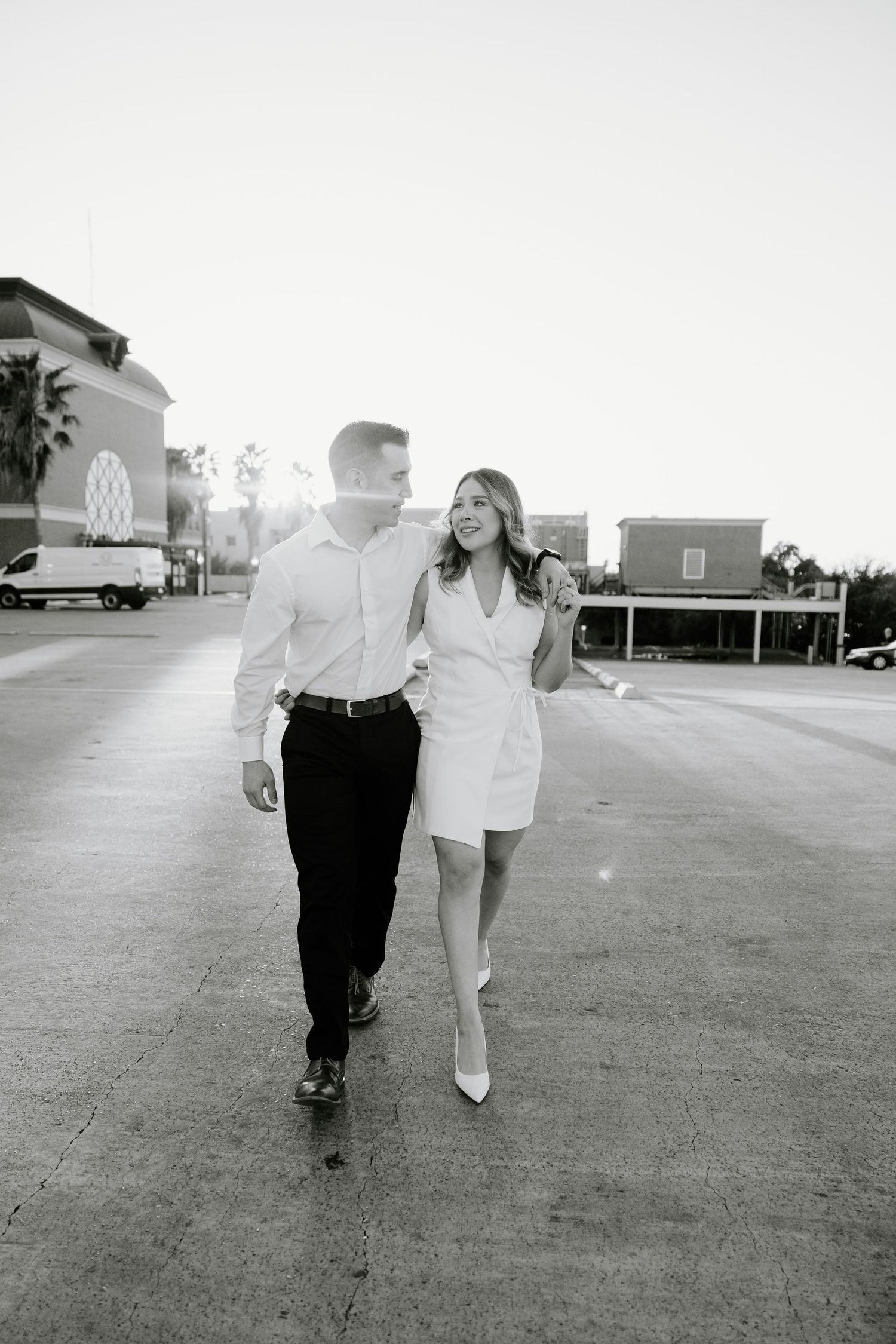 Black and white photo of a couple walking together on a paved outdoor surface.