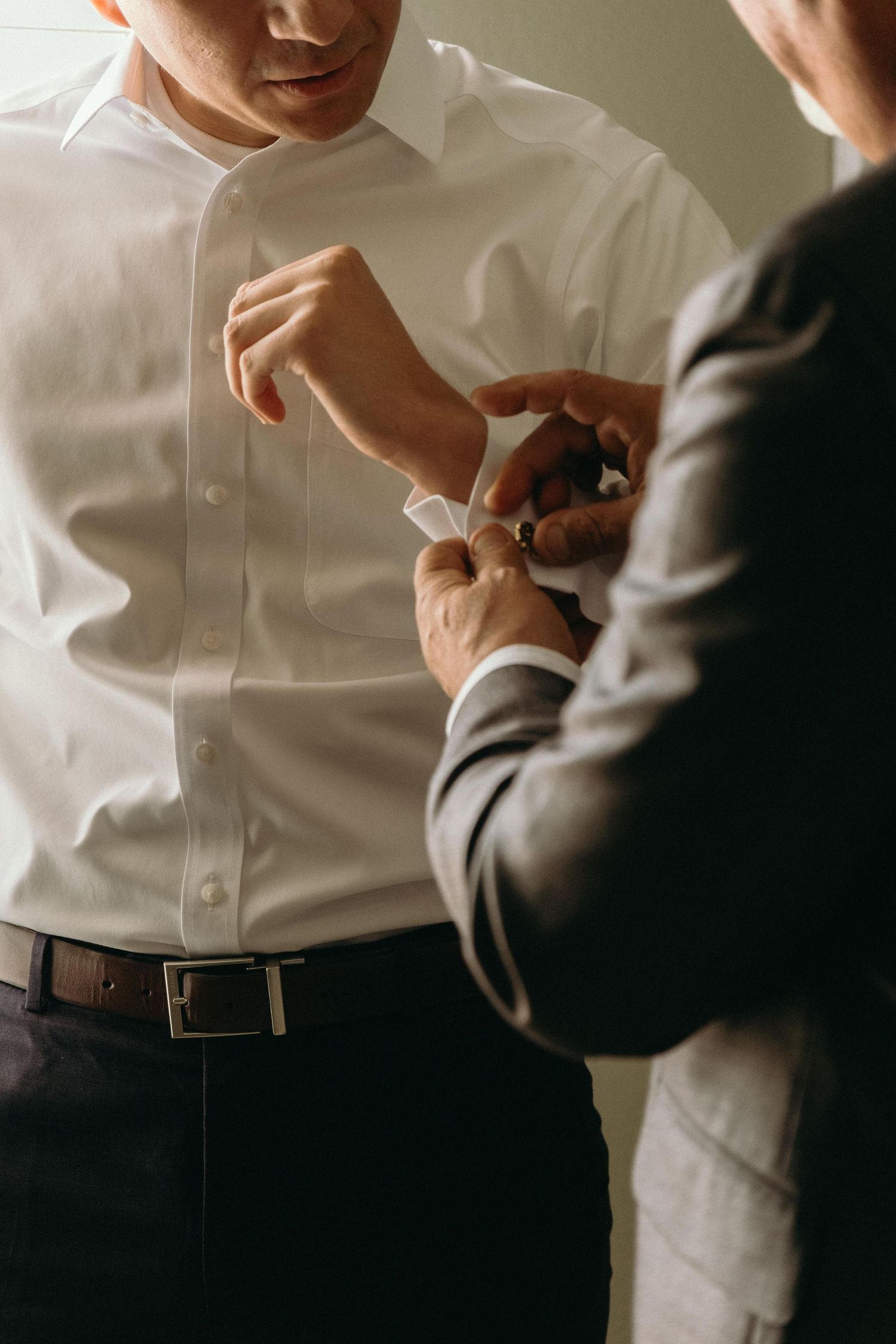 Detail shots of groom getting ready and adjusting formal attire.