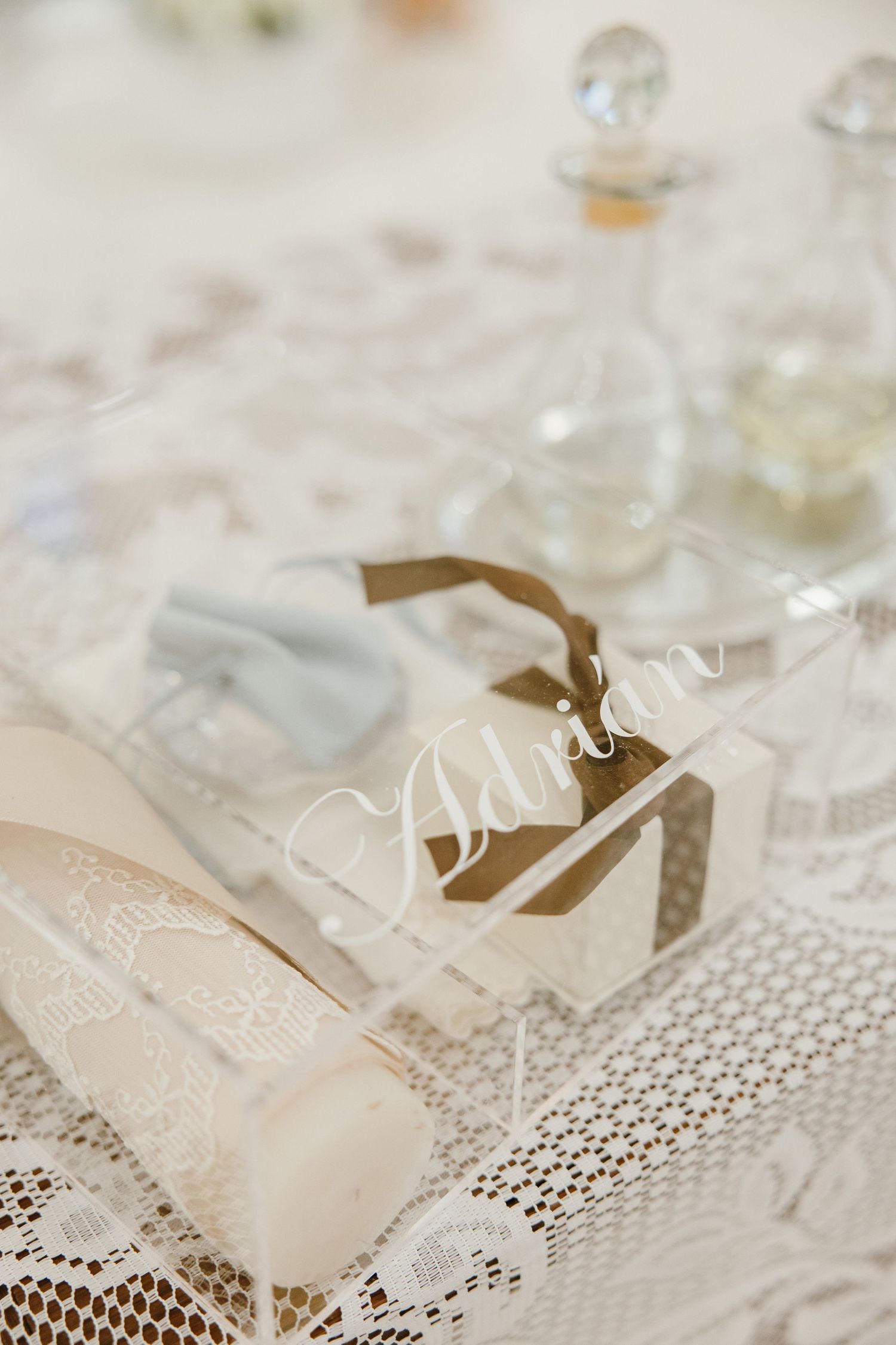 Elegant wedding place cards with delicate script displayed on white lace tablecloth.