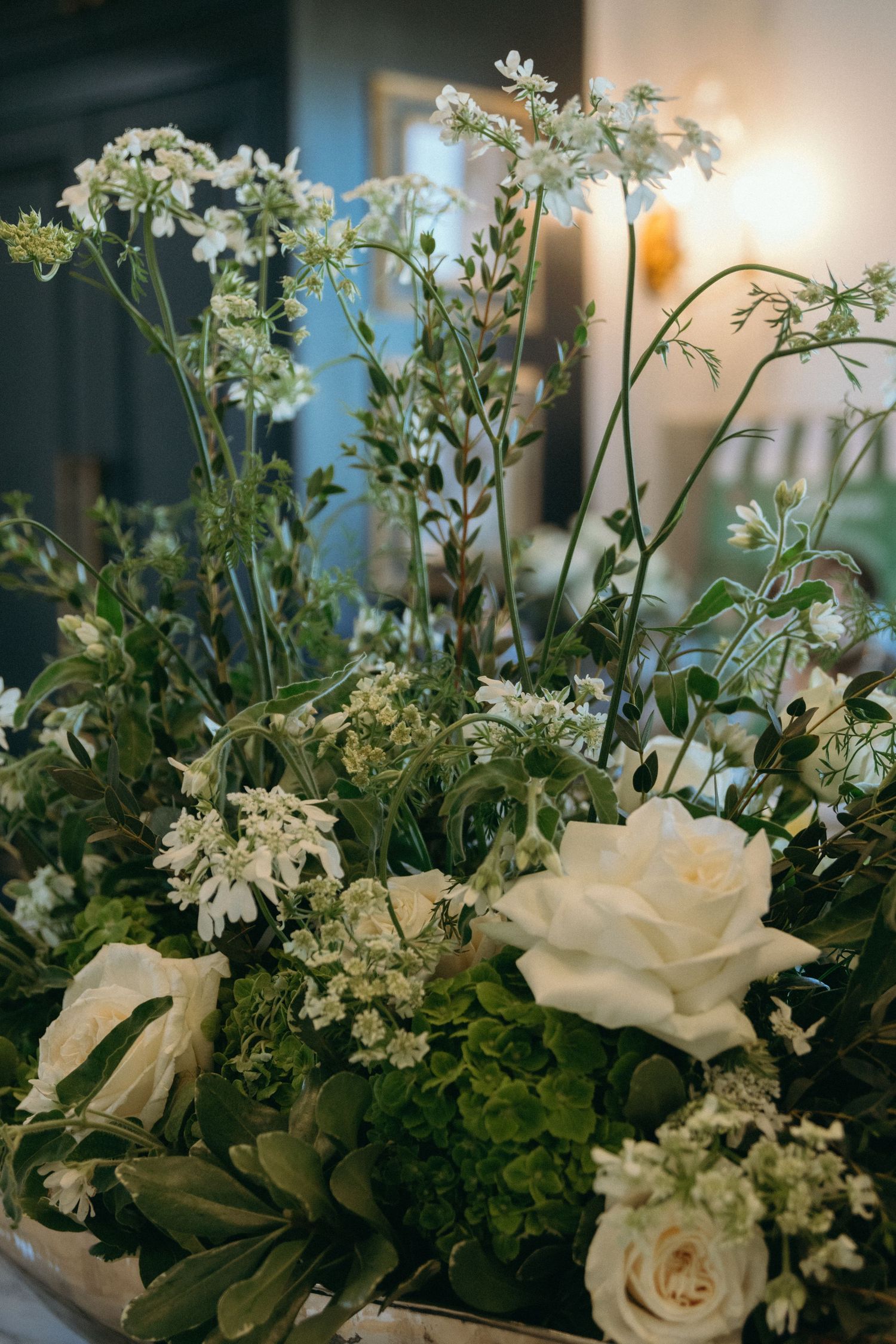 Elegant white floral arrangement featuring roses and delicate blooms with greenery.