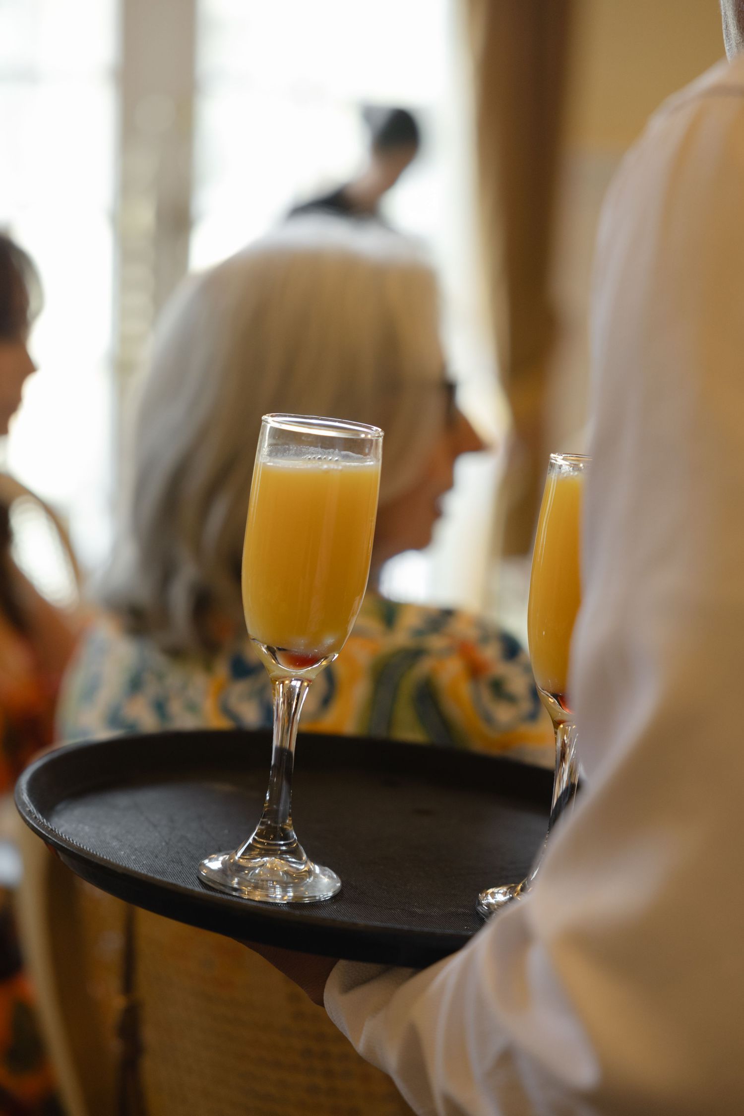Server holding a tray with champagne glasses at an elegant event.