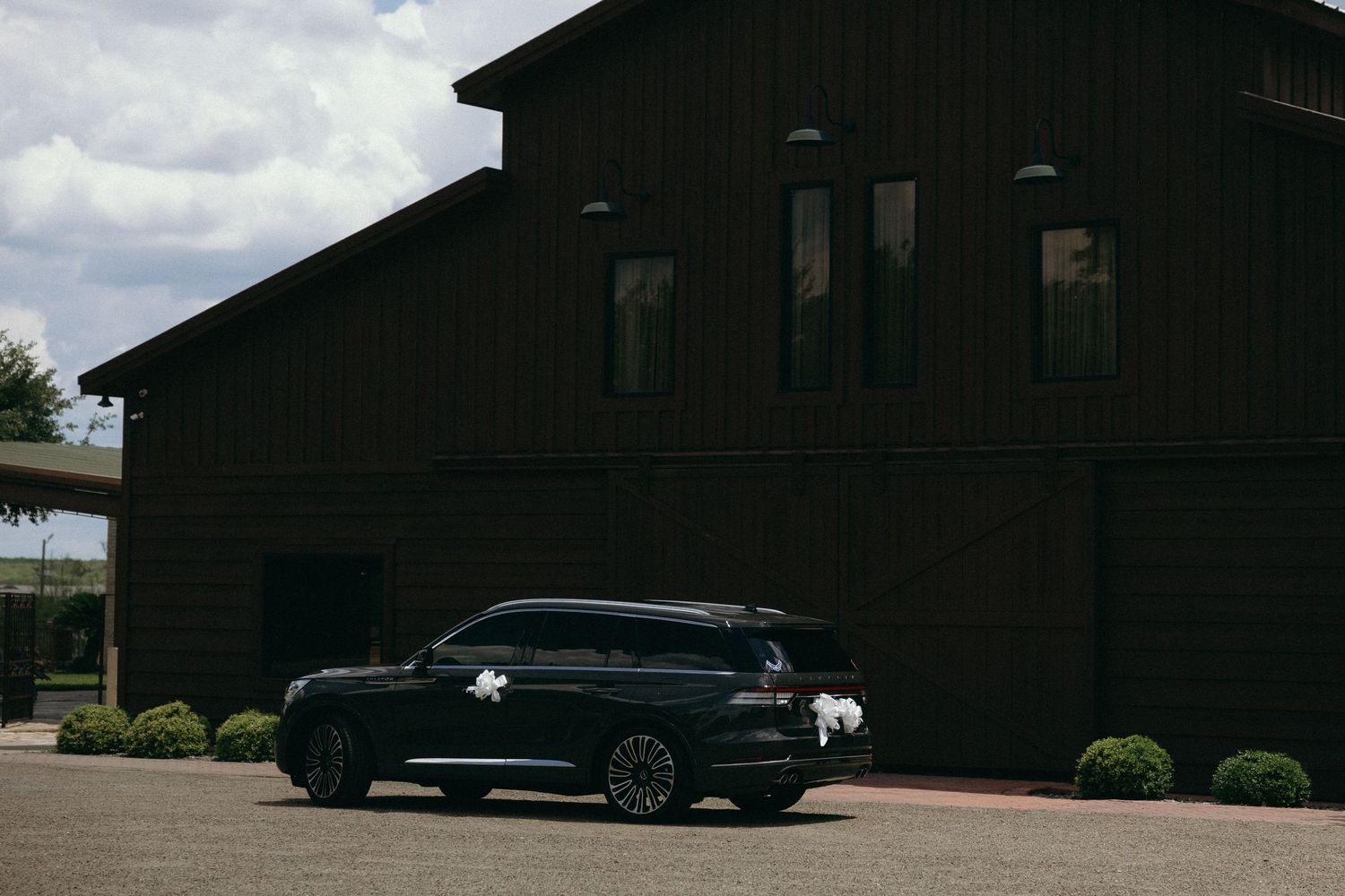 Dark exterior buildings with luxury vehicles parked outside under cloudy skies.