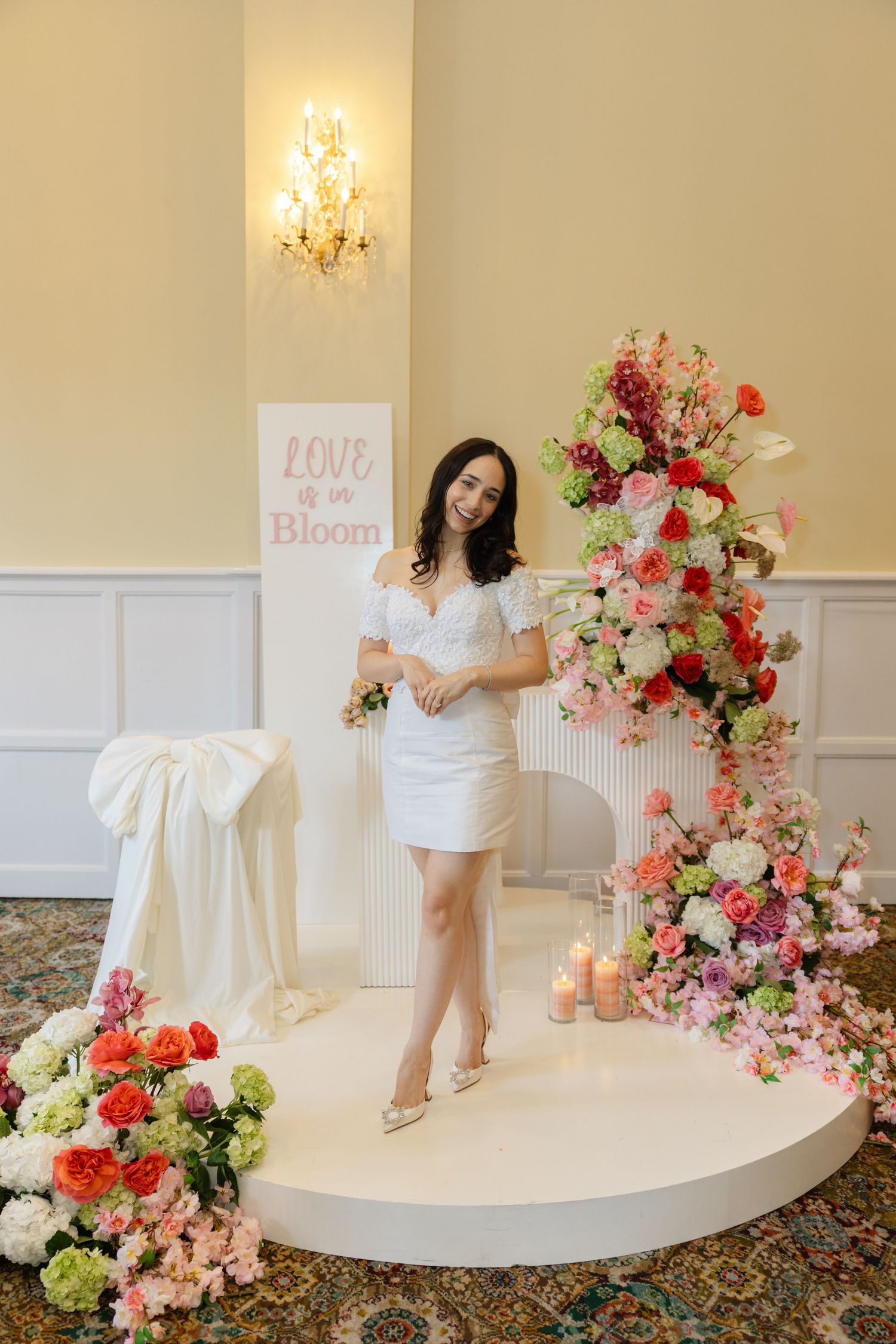 White platform stage decorated with vibrant floral arrangements and romantic decor elements.
