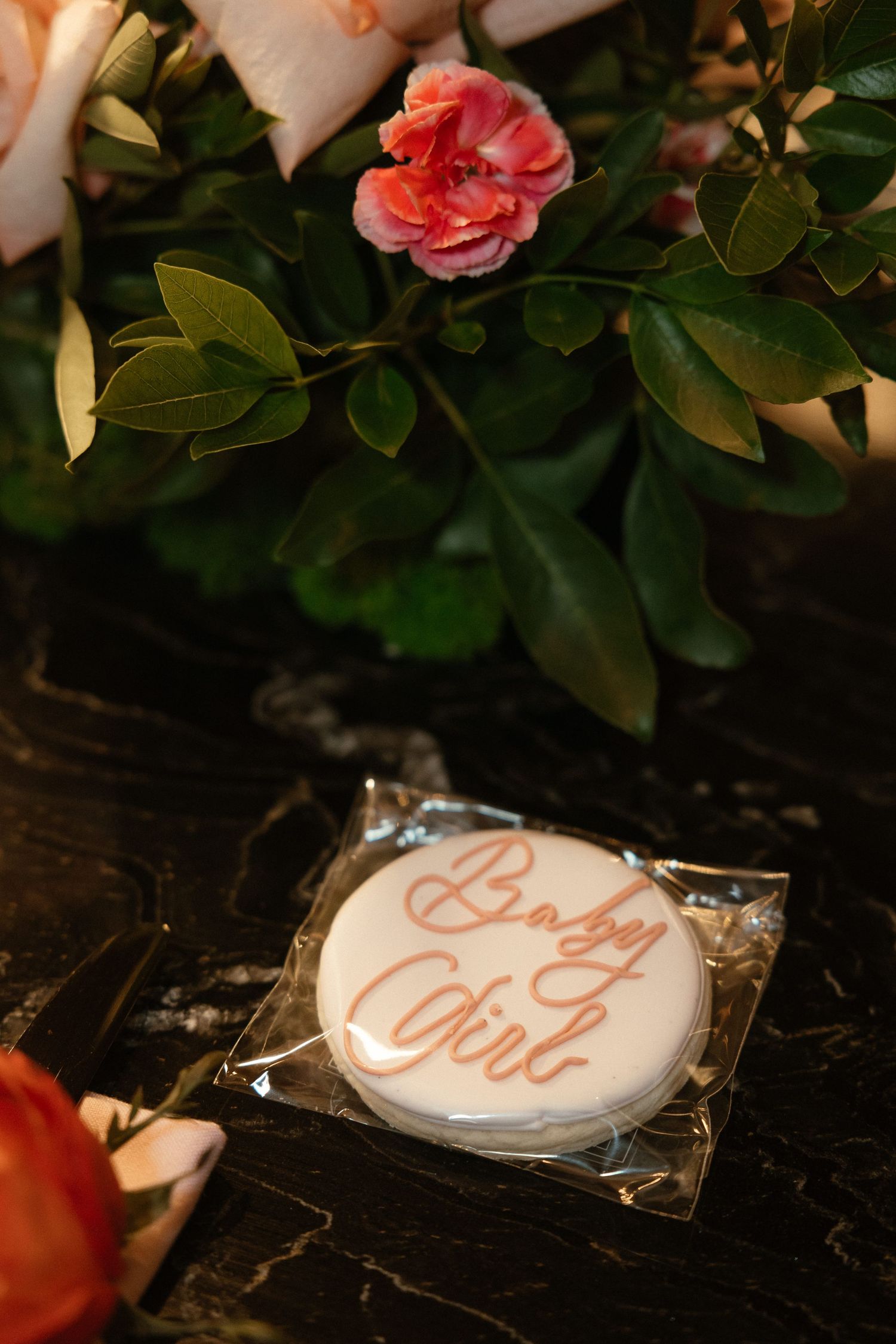 Close-up of a baby girl cookie with pink floral decorations.