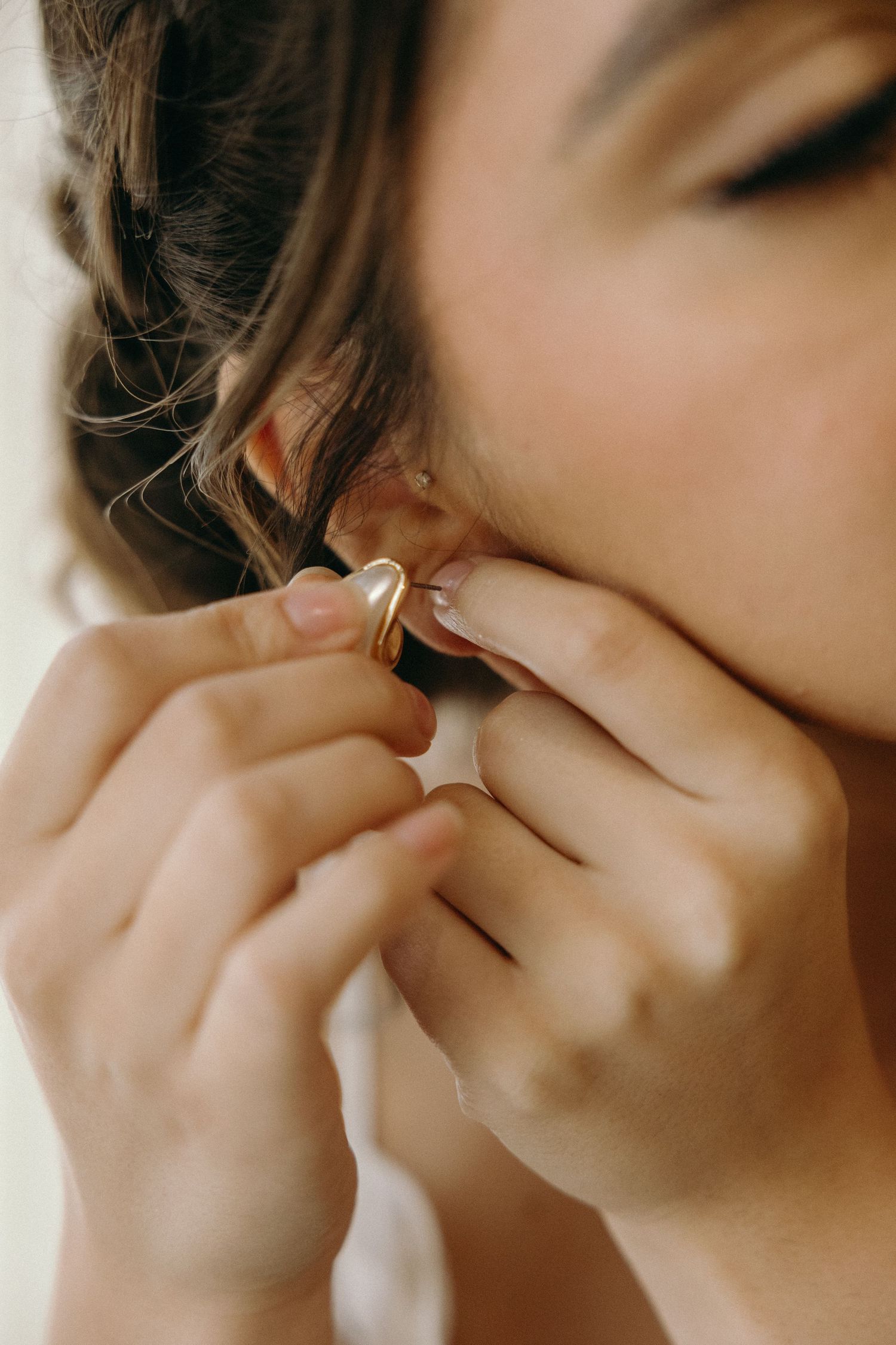 Close-up shots of hands putting on delicate jewelry in natural light.