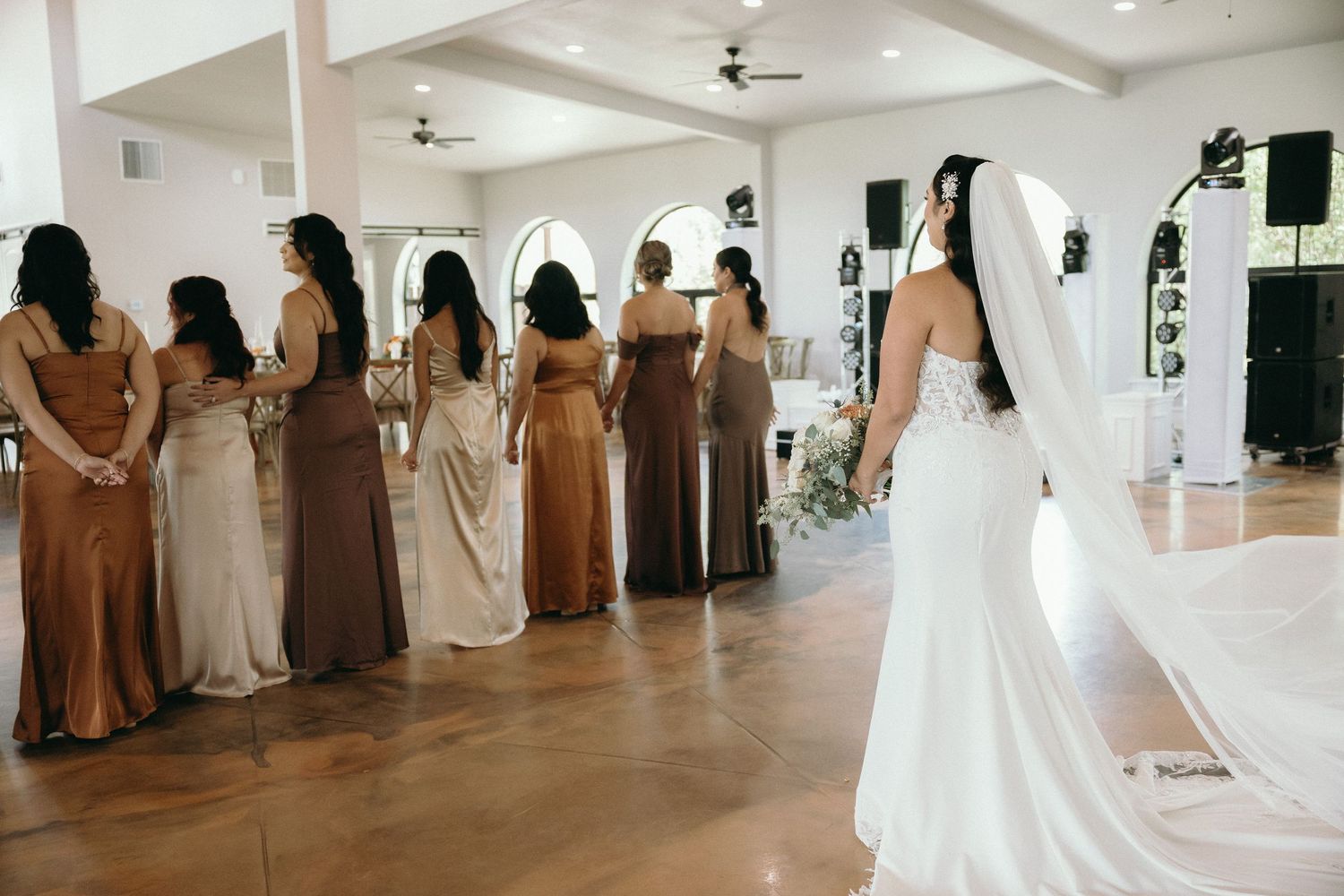 Wedding party lined up in elegant white venue with bridesmaids in champagne colored dresses.