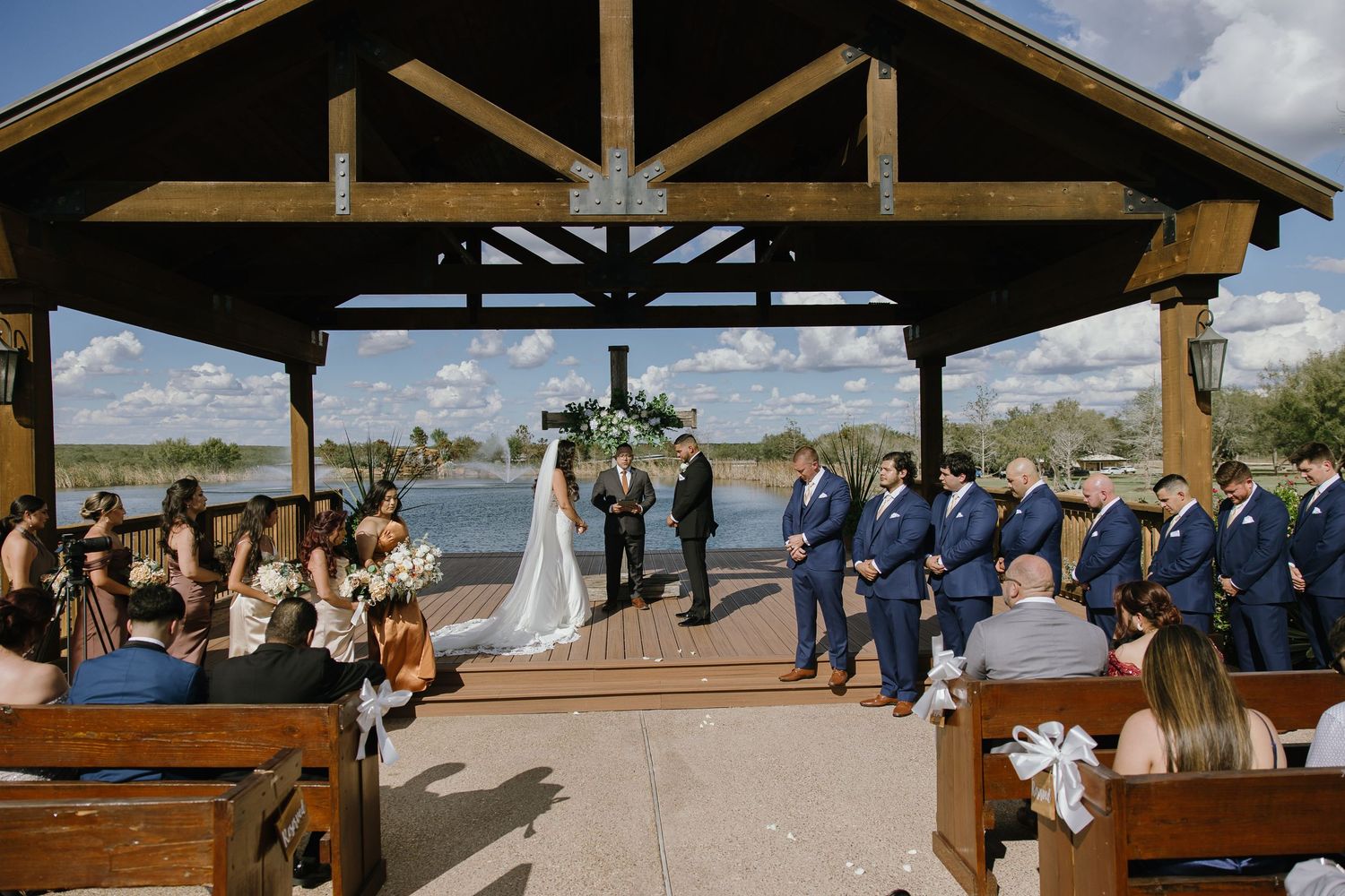 Rustic wooden pavilion set up for outdoor wedding ceremony with guests seated.