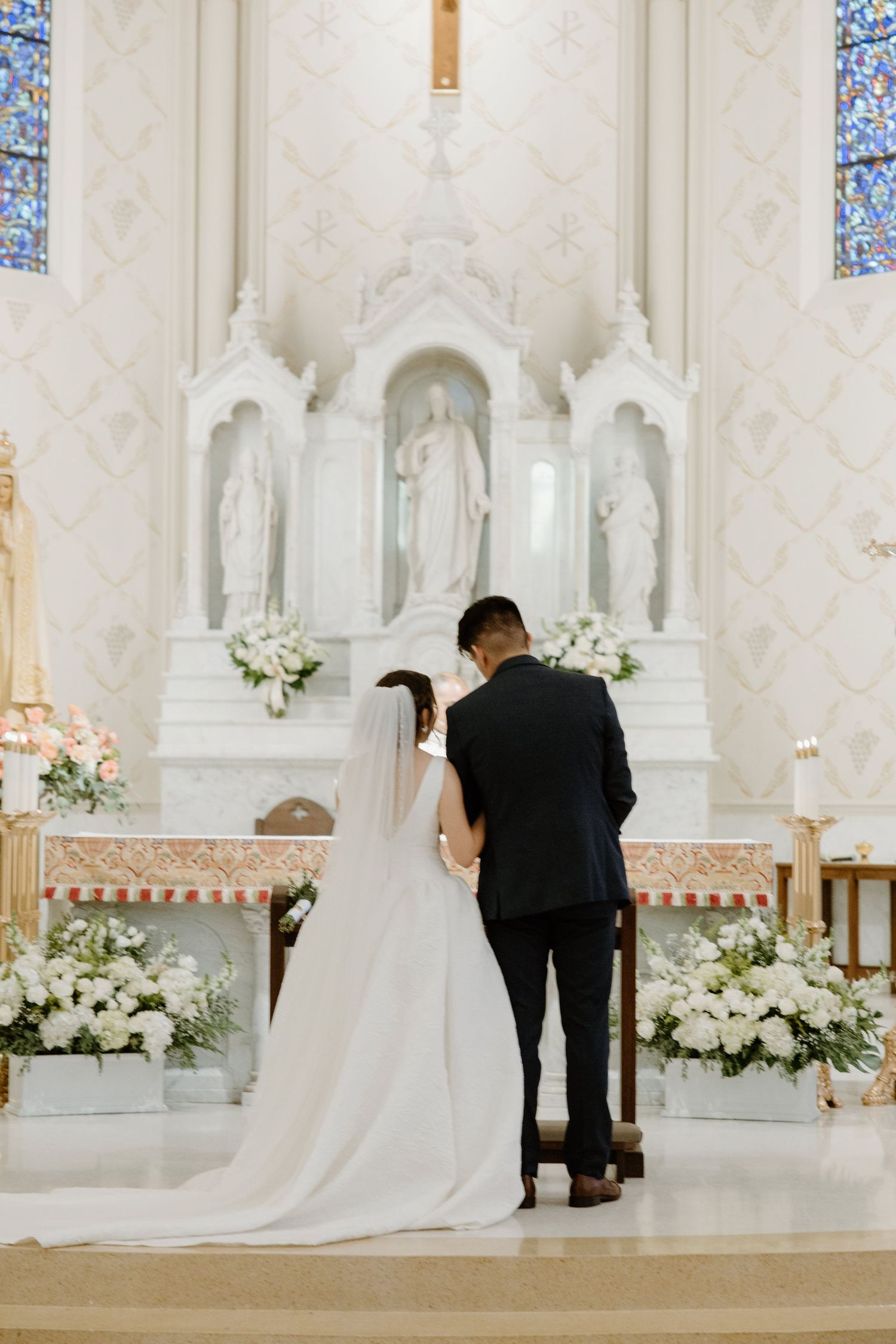 Wedding ceremony sequence in elegant white church with floral altar decorations.