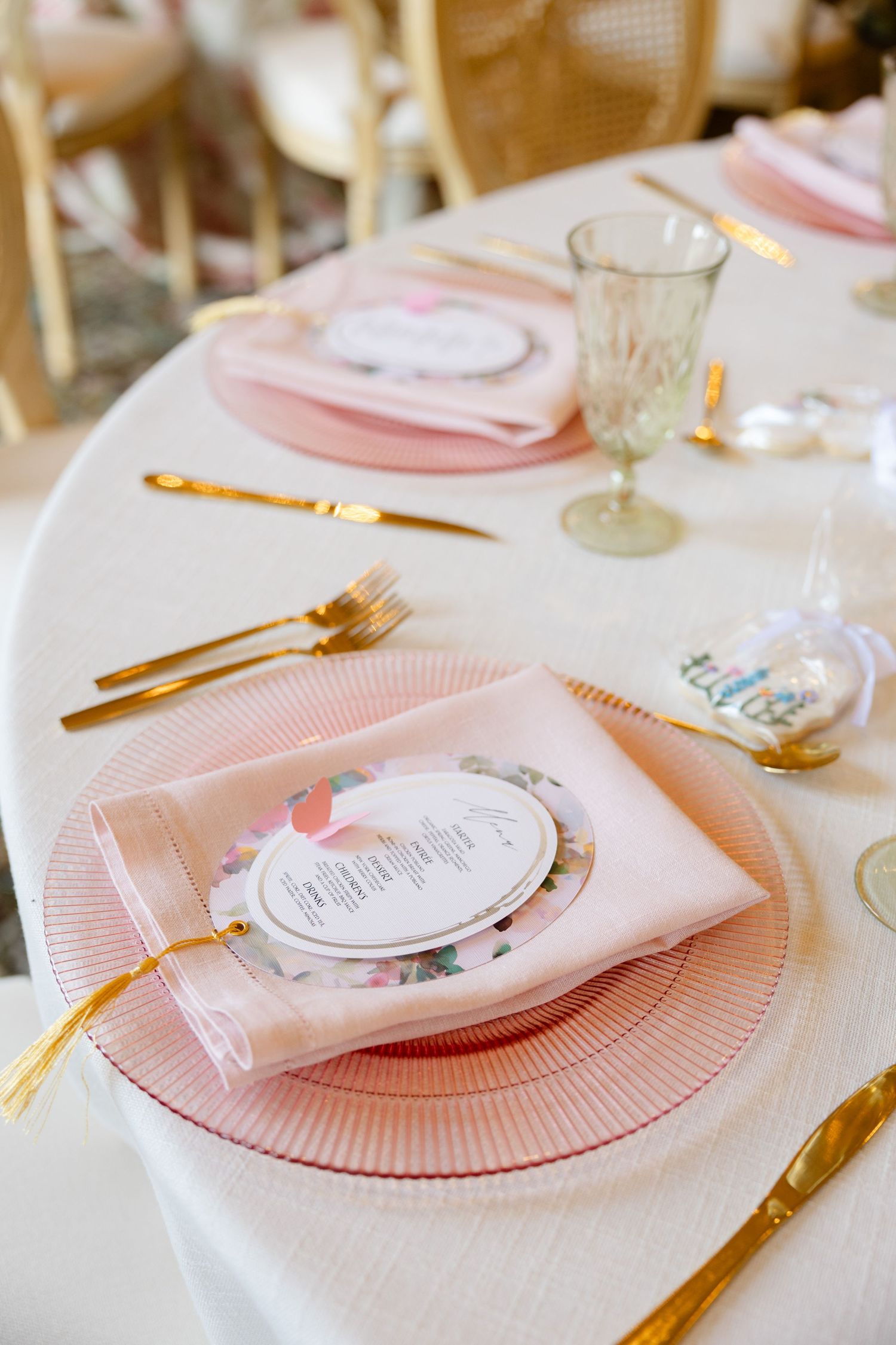 Elegant table setting with pink charger plates and gold cutlery.