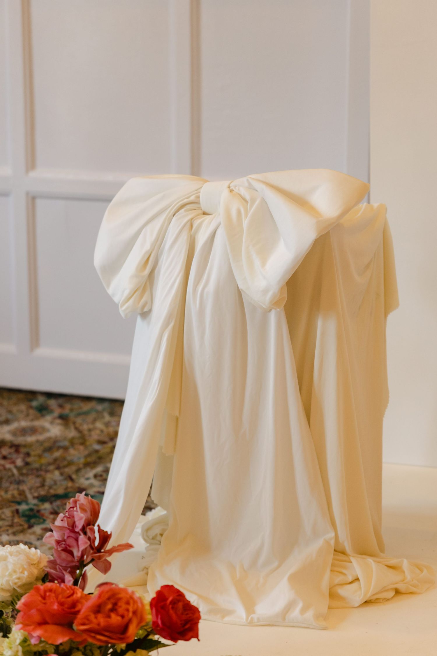 Elegant white draped fabric with pink and orange flowers as decoration.