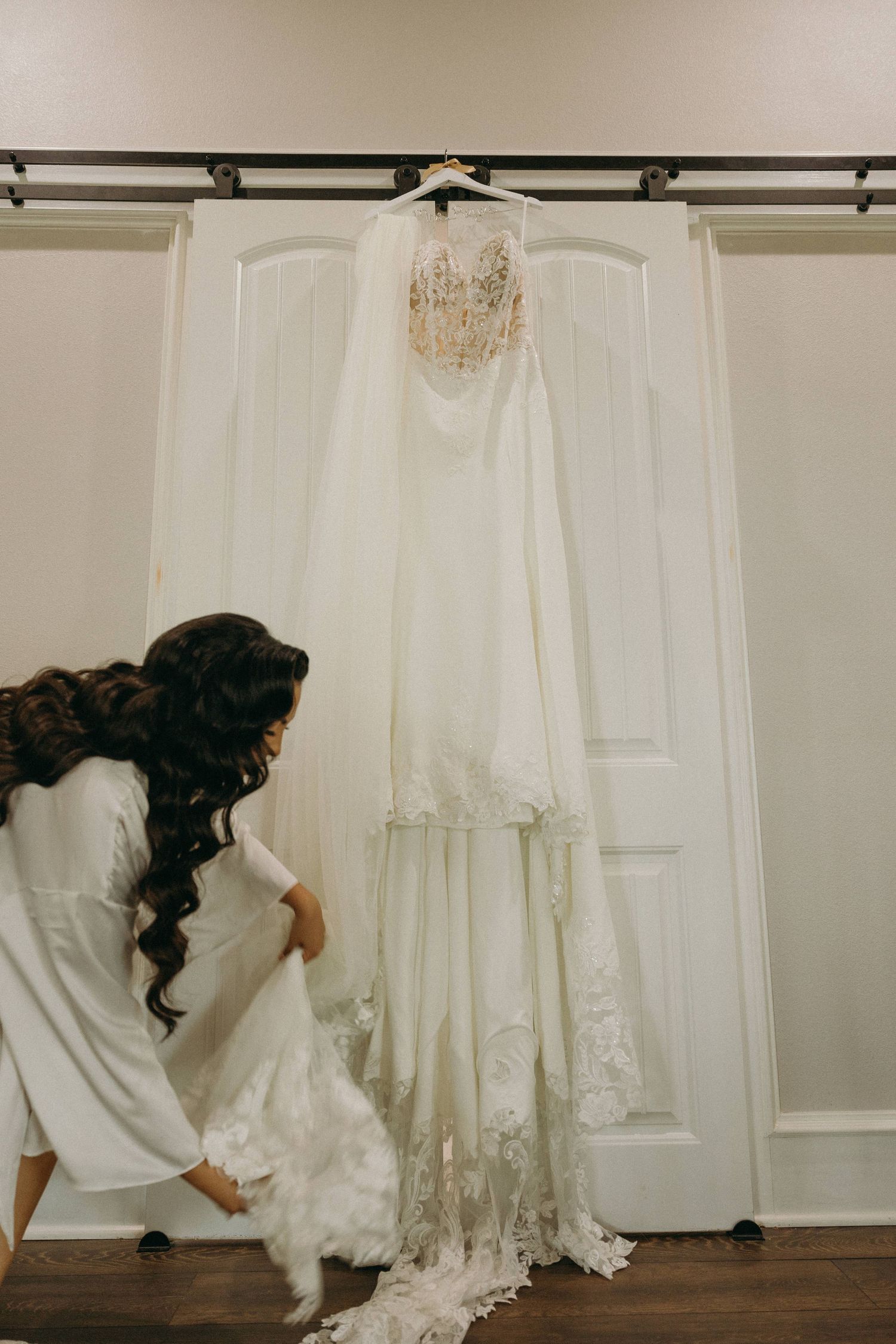 Wedding dress being steamed and prepared before the ceremony against a white door backdrop.