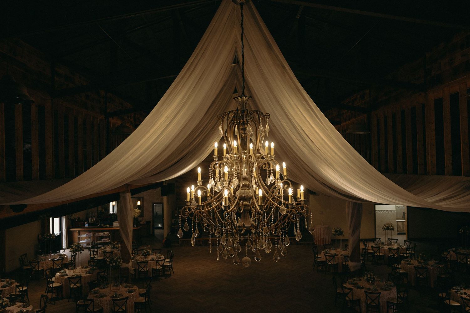 Elegant wedding venue interior with draped fabric and crystal chandeliers creating a romantic atmosphere.