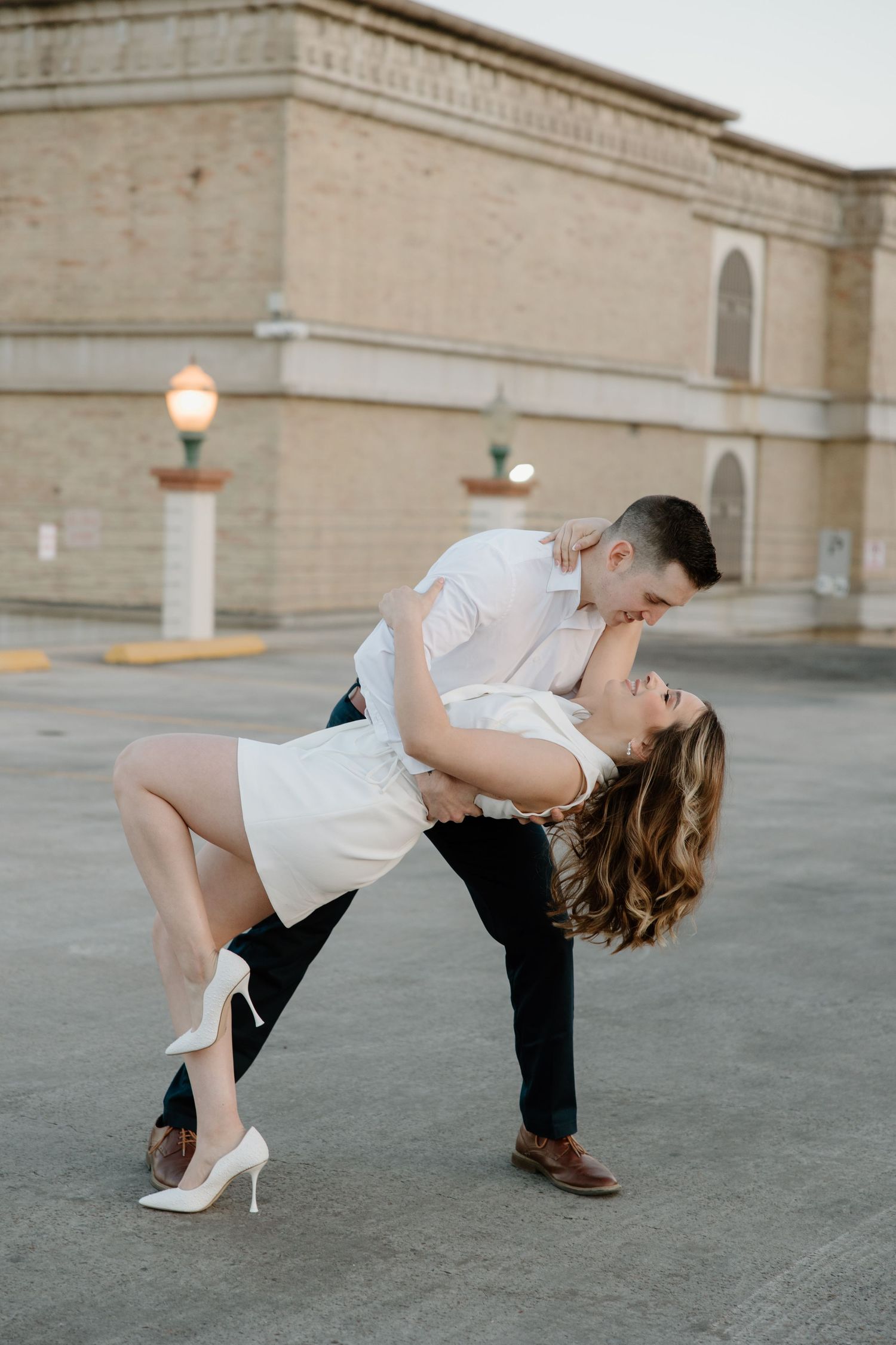 Romantic dip dance pose sequence on concrete plaza with palm trees in background.