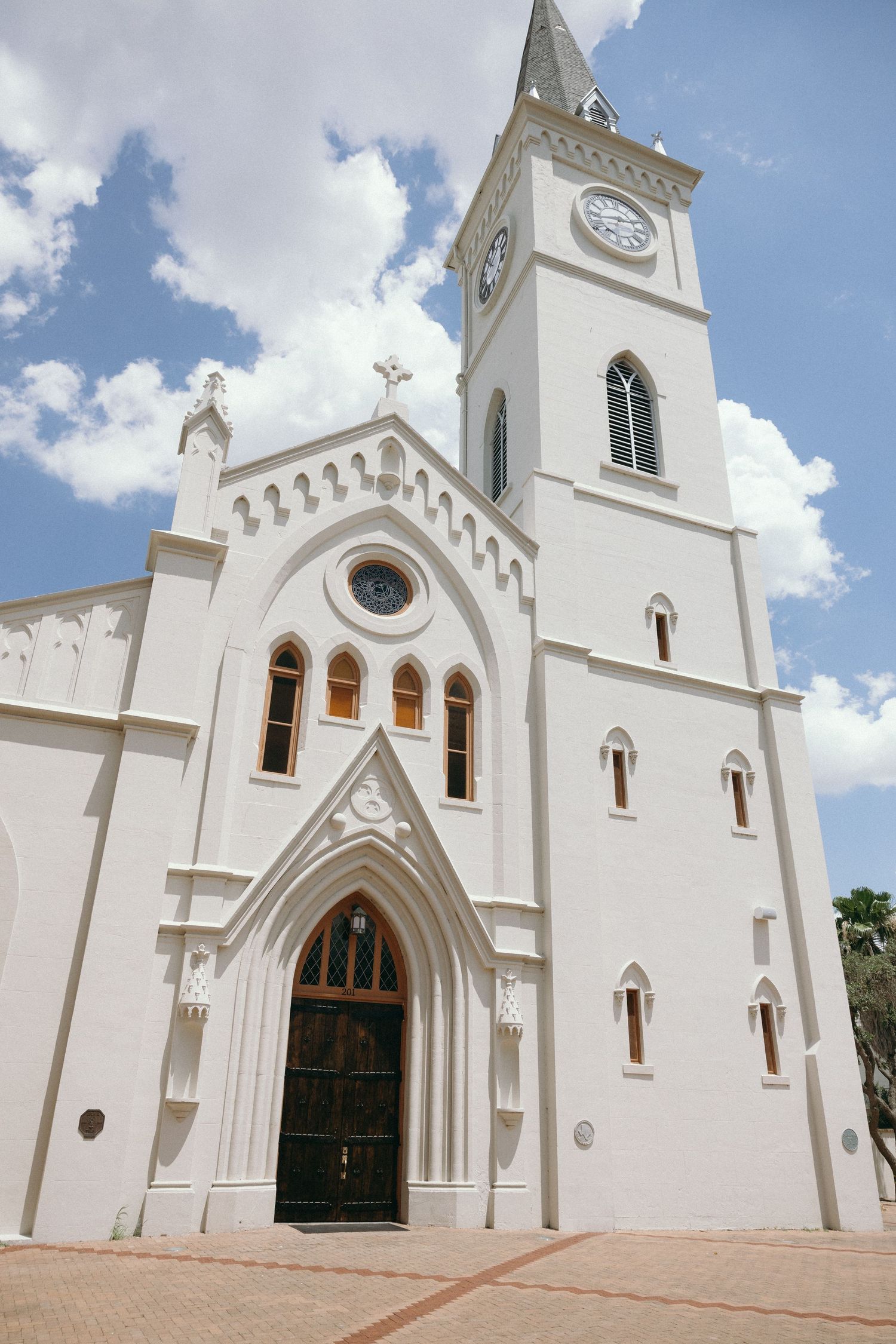 White Gothic revival church exterior with pointed arches and bell tower against blue sky.