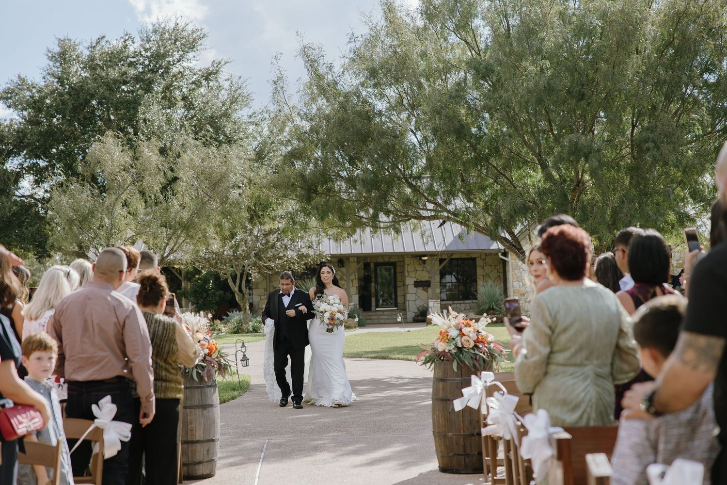 Outdoor wedding ceremony setup with rows of white chairs under trees.
