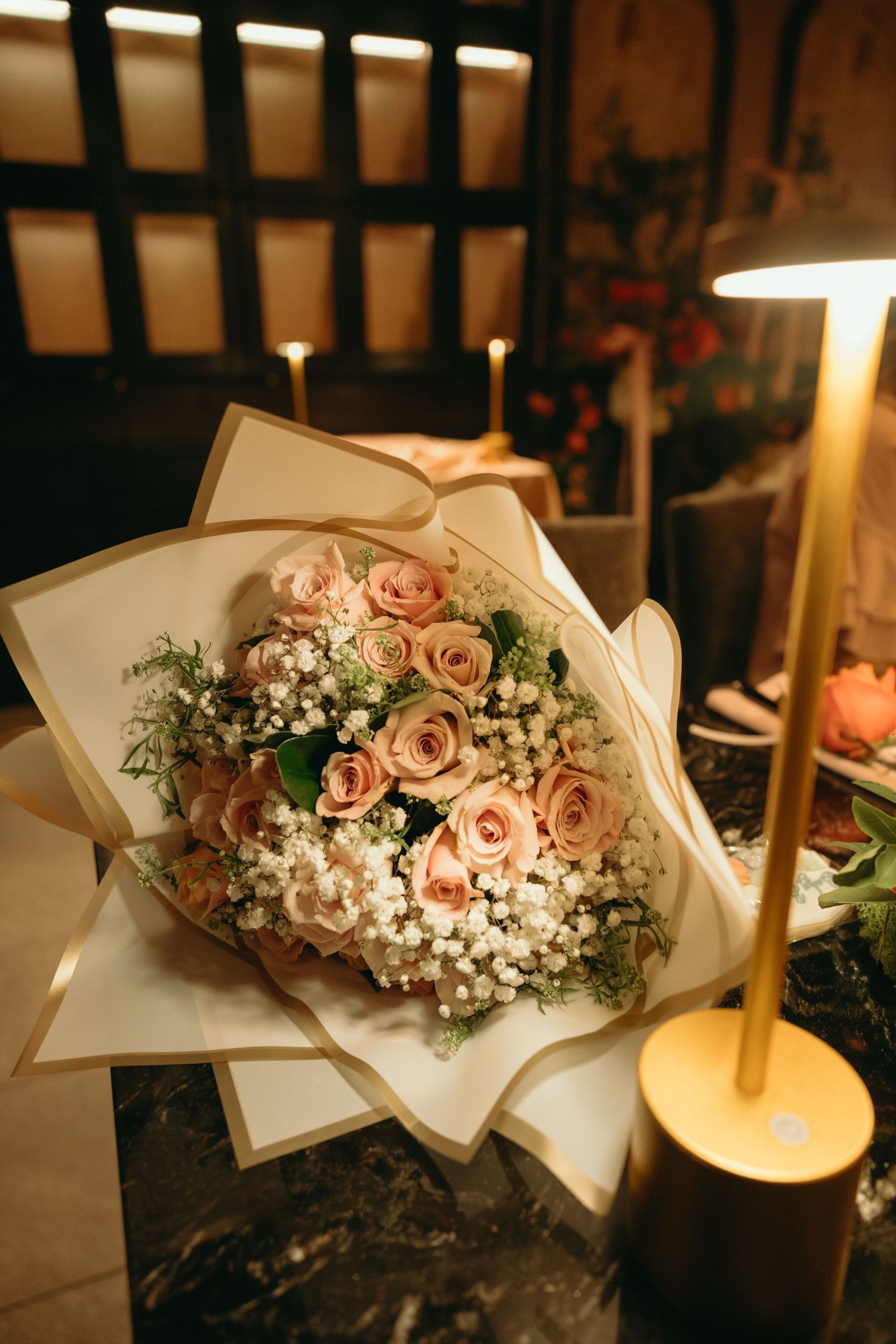 Beautiful floral arrangements with pink roses and baby's breath displayed on a candlelit table.