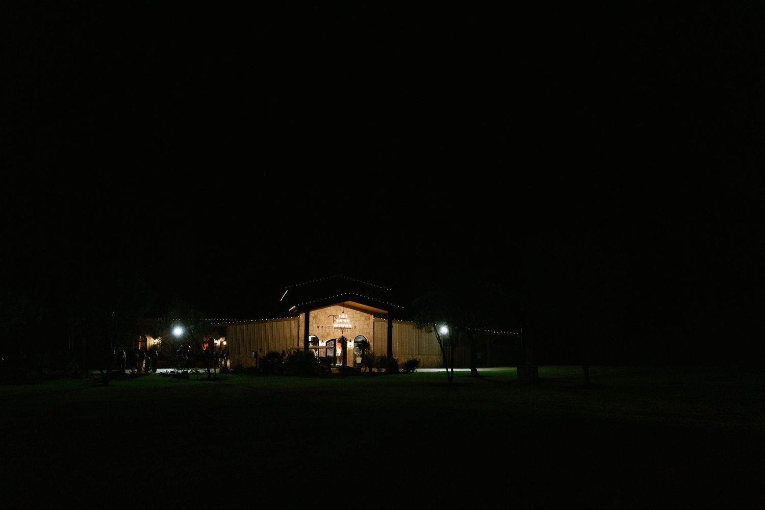 A dimly lit wedding venue glows warmly against the night sky.
