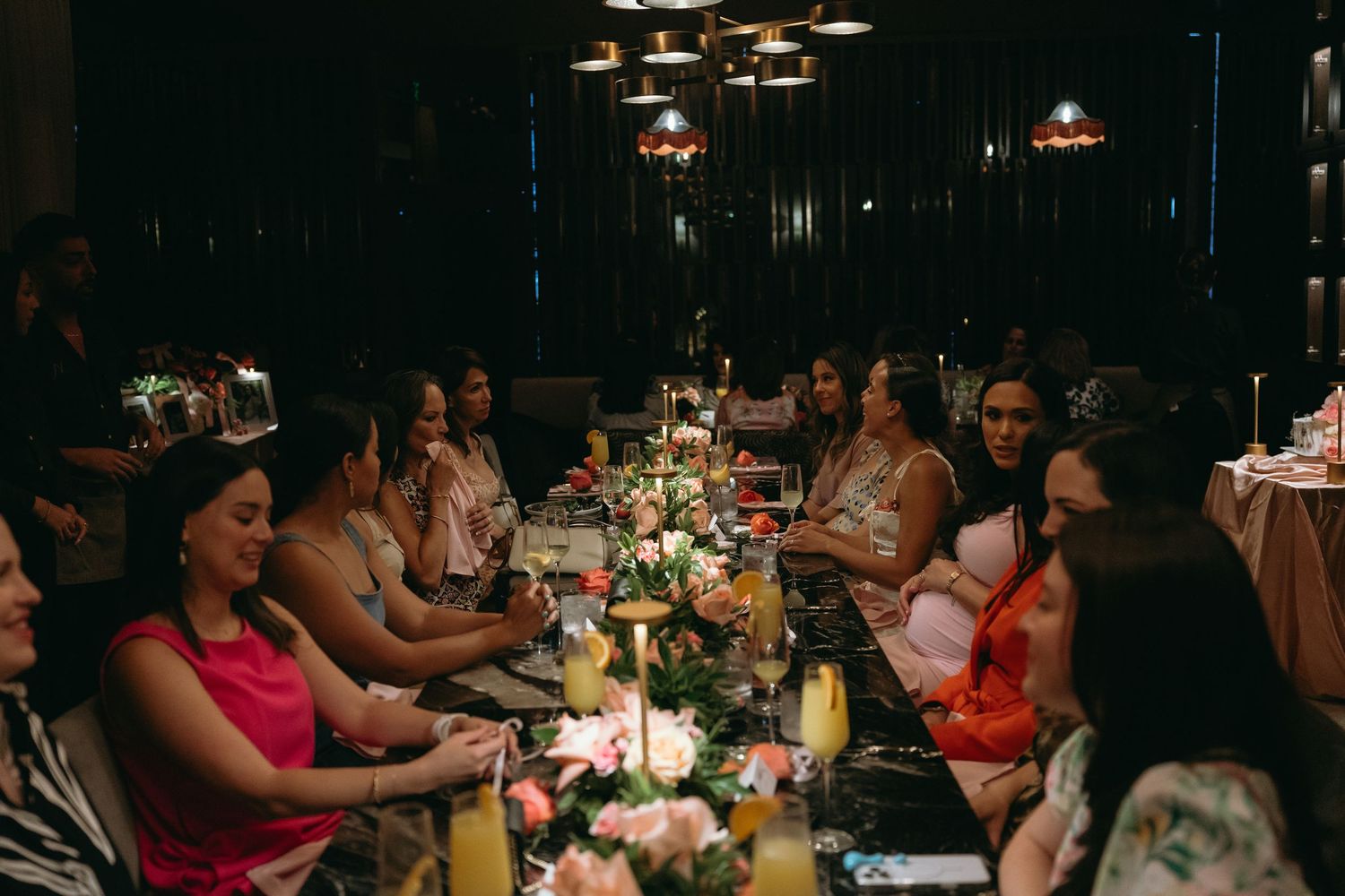 Dimly lit event space with guests seated at decorated dining tables.