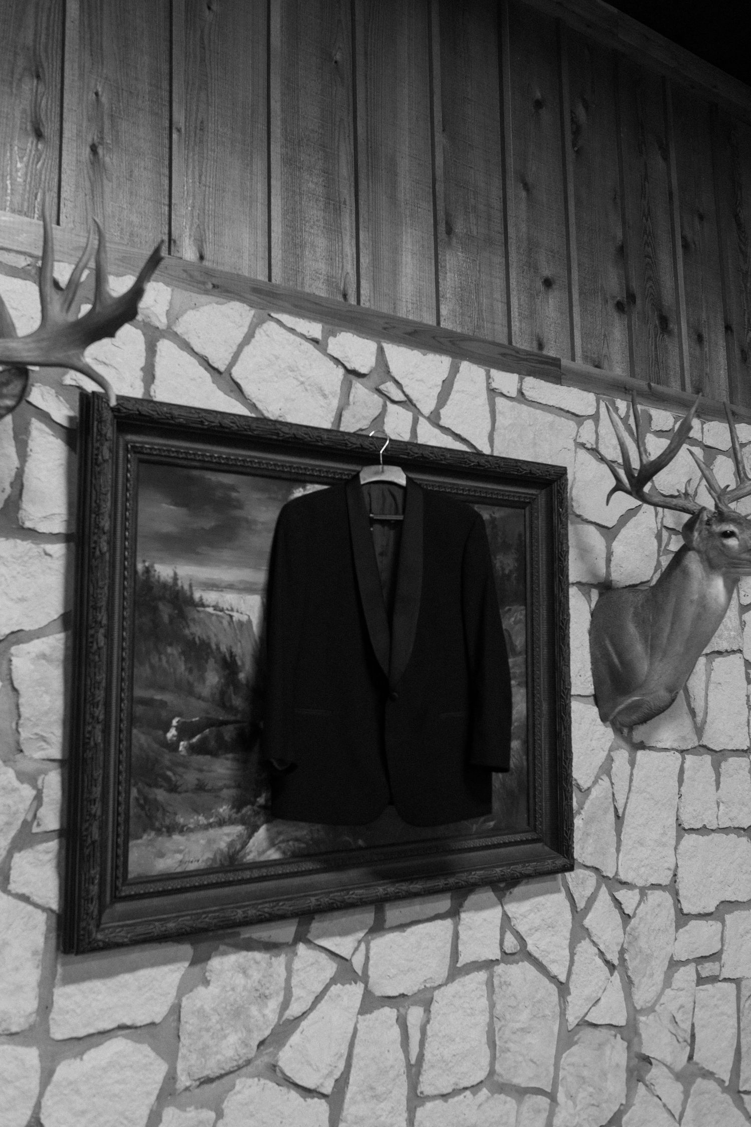 Row of framed artwork hanging on rustic stone and wood wall.