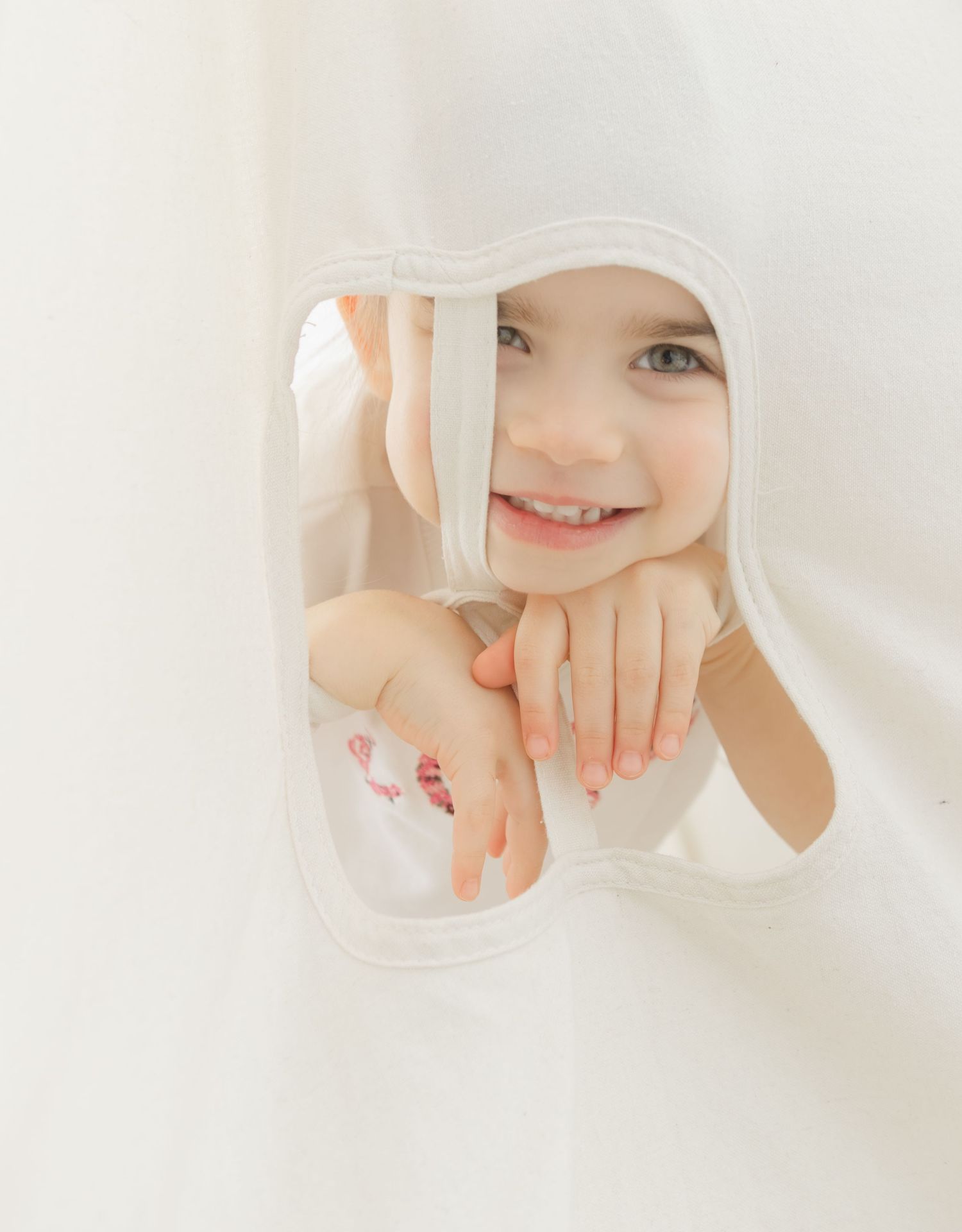 smiling little girl peeking through soft fabric playful child portrait studio photography St Albert