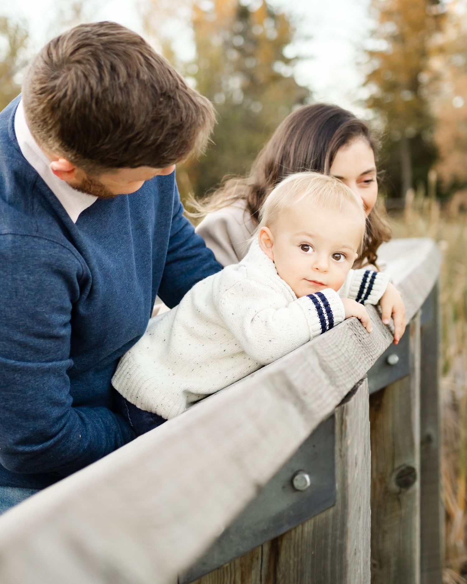 parents holding baby by wooden fence outdoor family photography St Albert Alberta