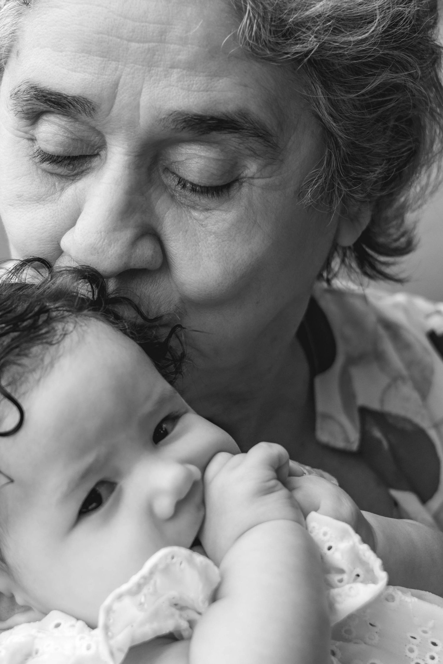 grandmother kissing baby on the head black and white family portrait