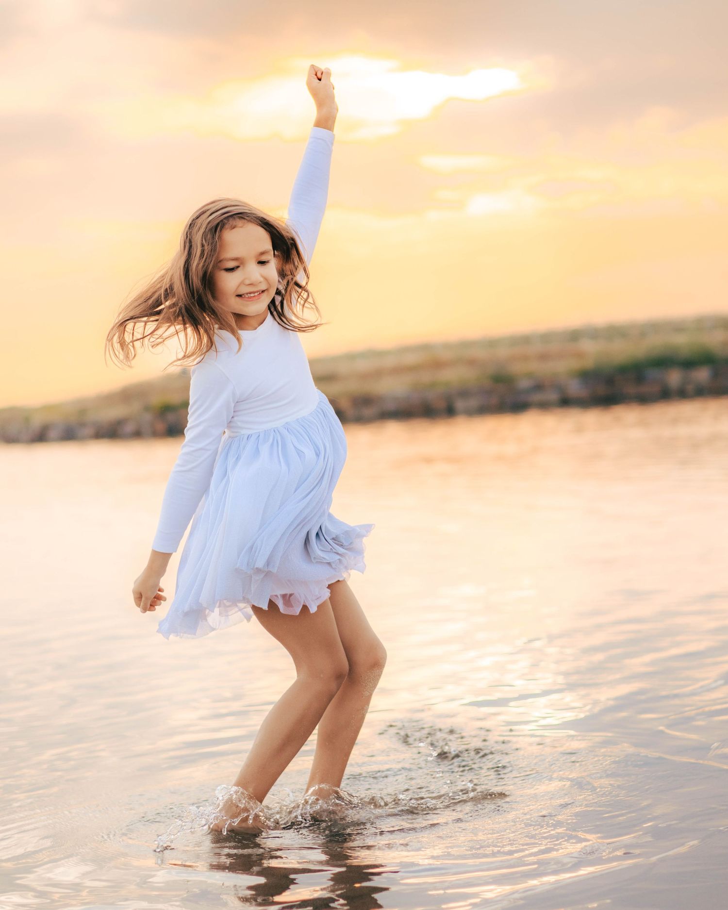 girl dancing in shallow water at sunset playful child portrait St Albert Alberta