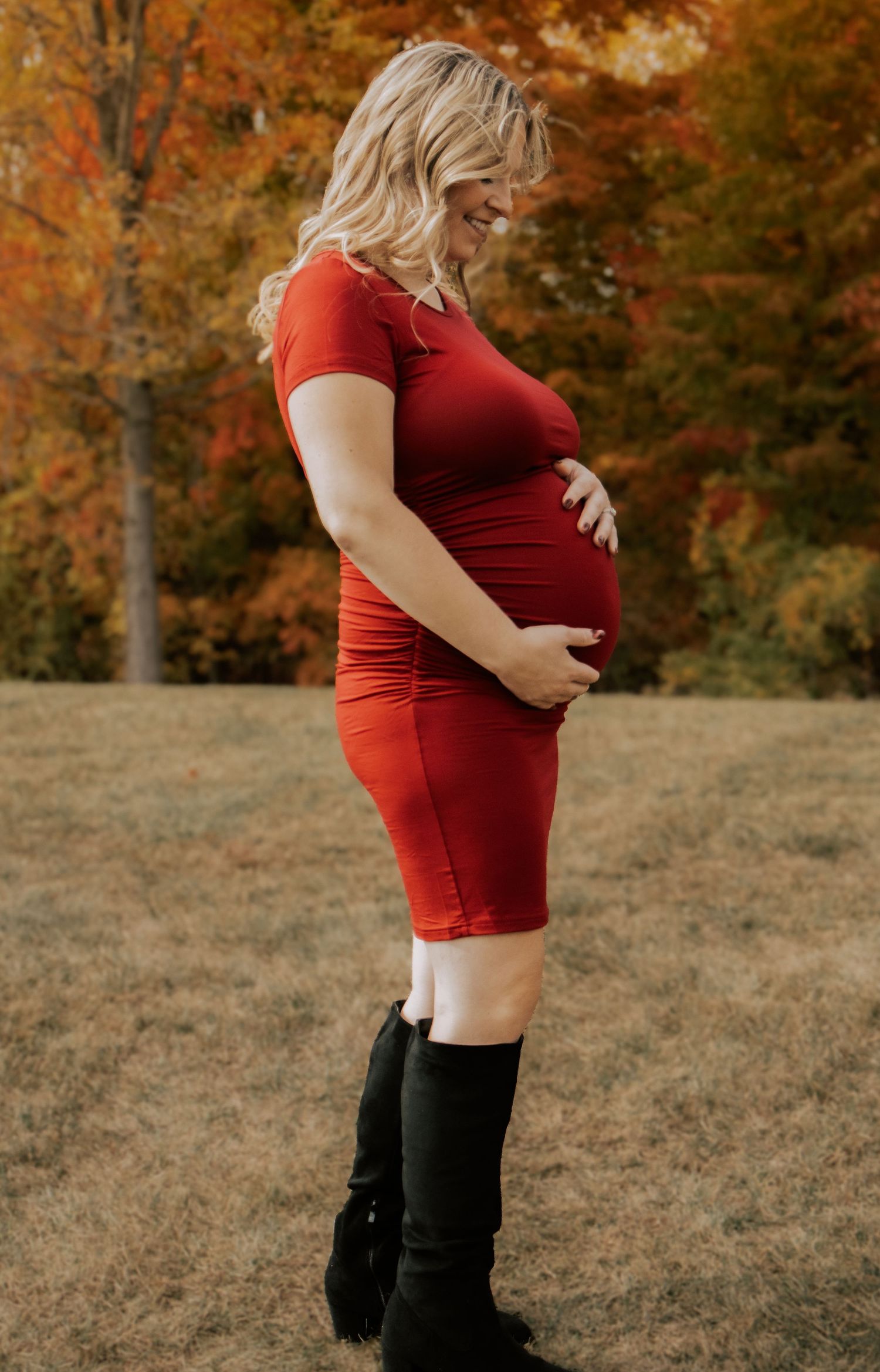 Close-up maternity photos showing a red dress against fall foliage.