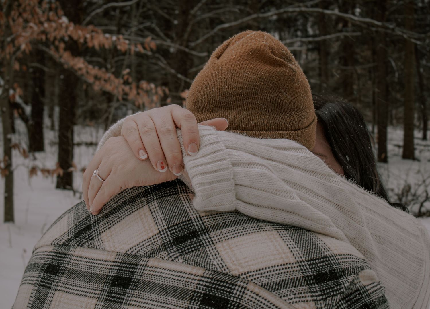 A snowy winter forest scene with a person in a plaid shirt looking out at the snow-covered landscape.