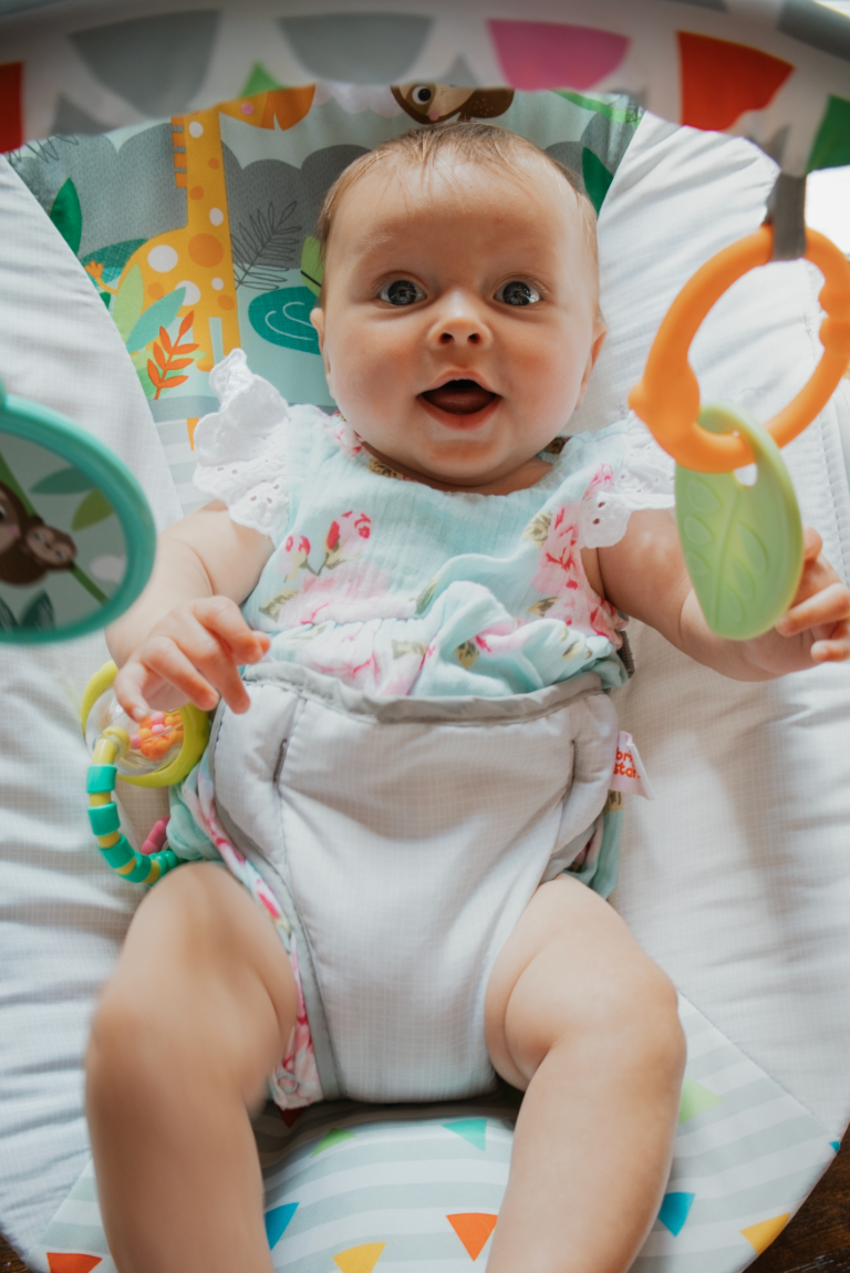 Infant lying on colorful playmat wearing white onesie and showing cheerful expressions in sequential photos.