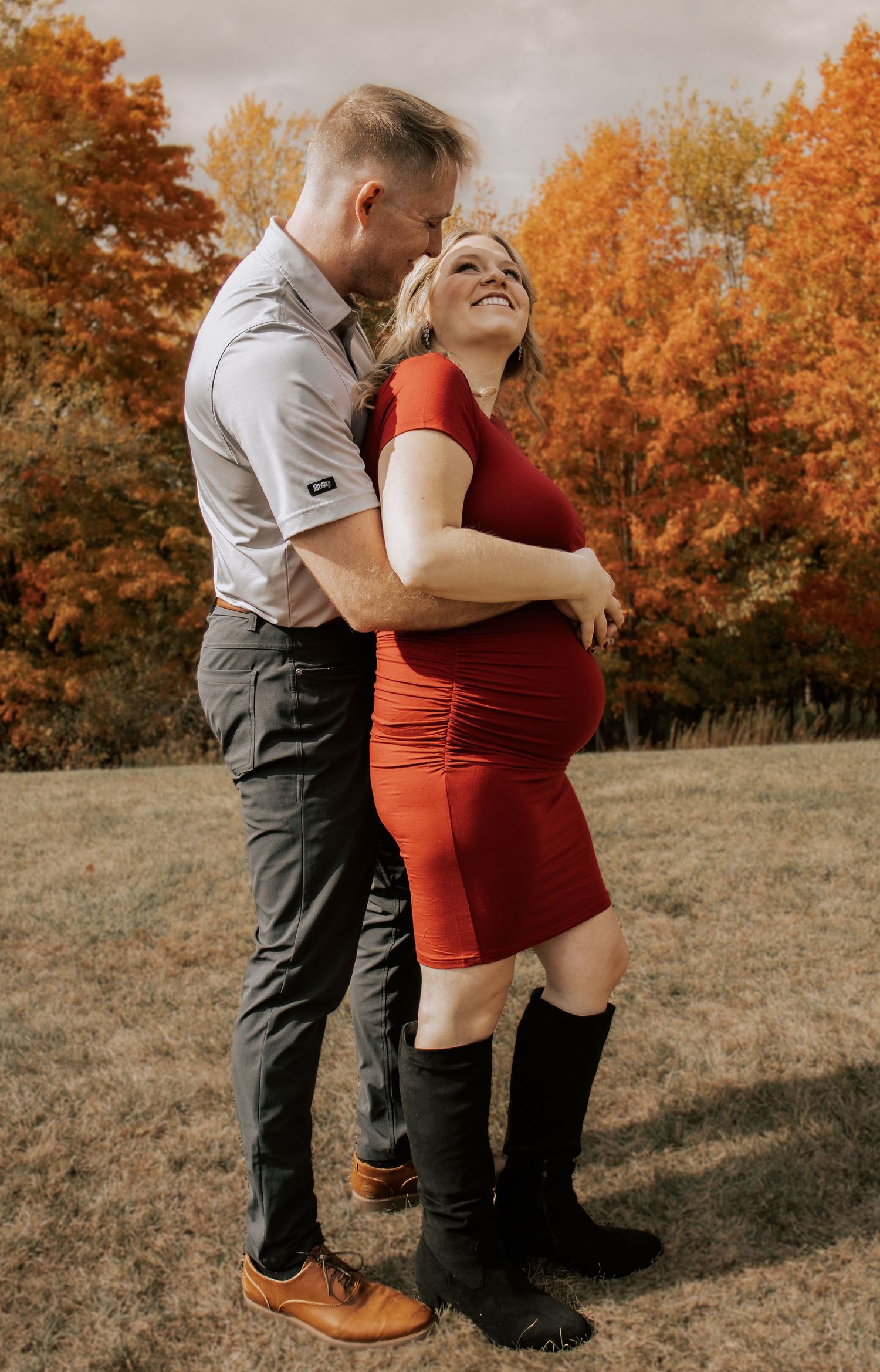 A couple shares an intimate moment in a field during autumn.