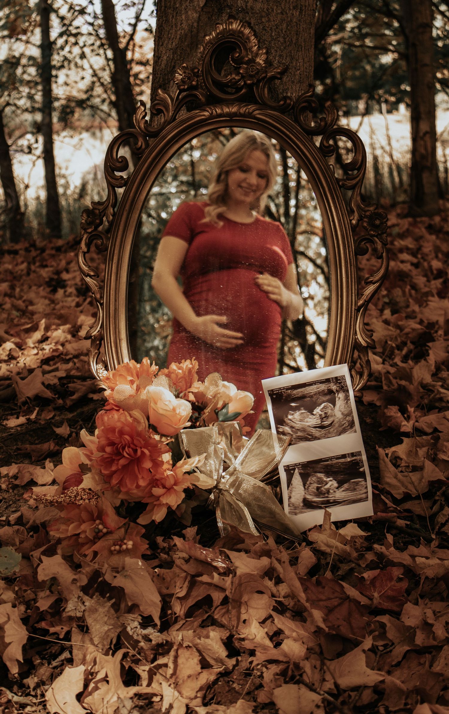 Artistic maternity photo with vintage mirror and fall leaves on the ground.